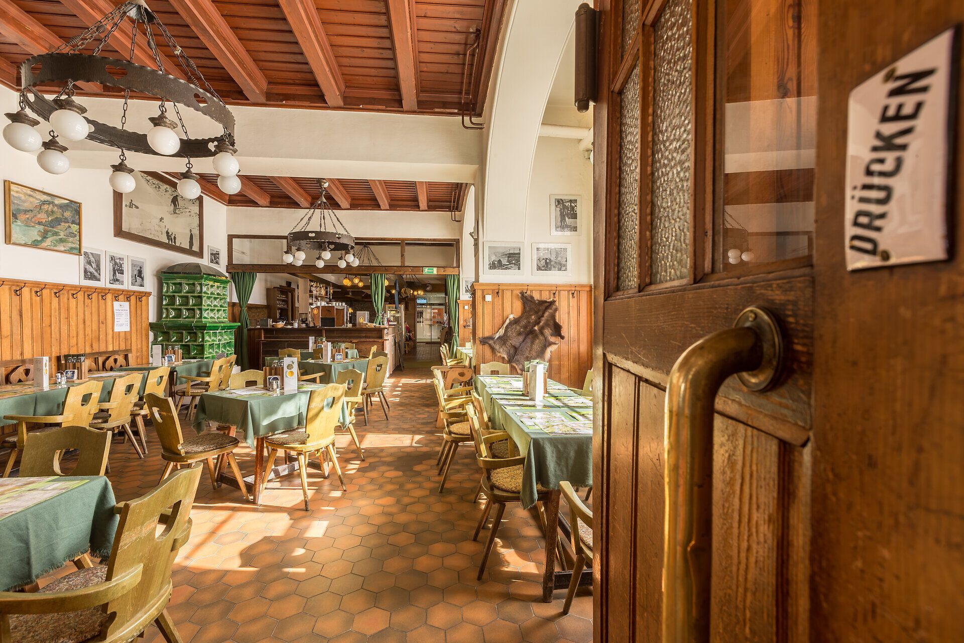 In einem einladenden Berggasthof strahlt die warme Atmosphäre des rustikalen Interieurs. Holztische und Stühle laden dazu ein, sich nach einem erlebnisreichen Tag in den Bergen zu entspannen und die köstlichen regionalen Spezialitäten zu genießen.