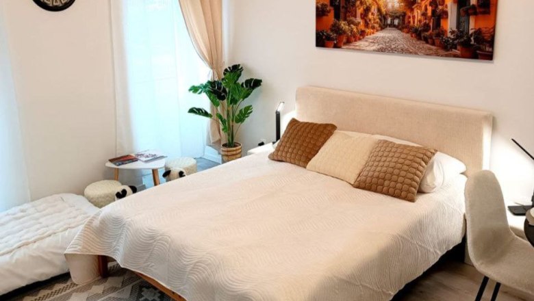 Gem&uuml;tliches Schlafzimmer mit Doppelbett, Pflanzen und Wandbild.