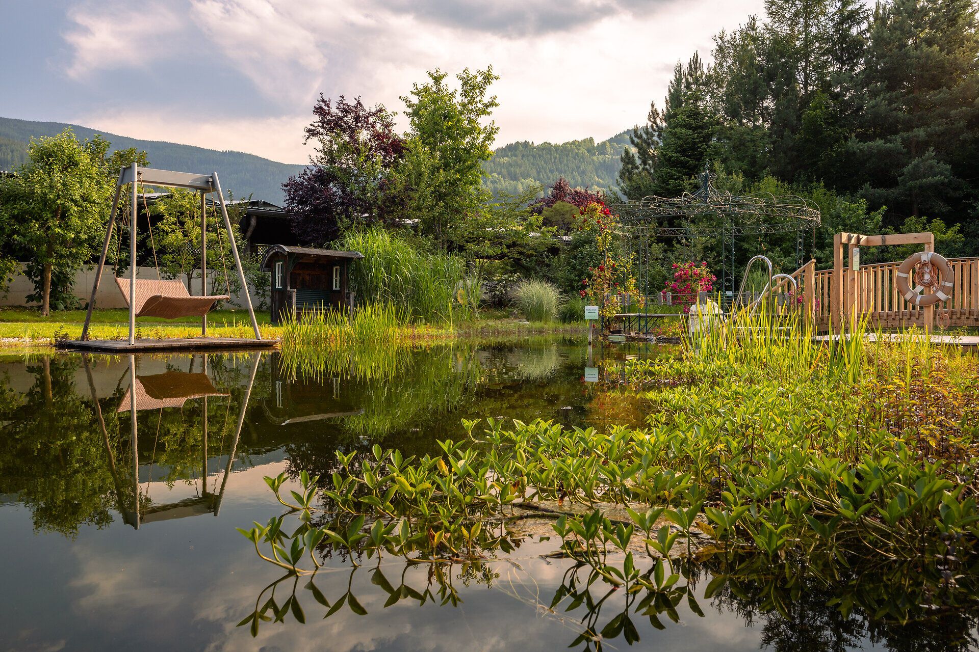 Ein idyllischer Ort, wo die sanften Wellen des Wassers die umliegende Natur spiegeln. Die schaukelnden Bäume und die blühenden Pflanzen schaffen eine harmonische Atmosphäre, die zum Entspannen einlädt. Hier kann man die Ruhe der Natur in vollen Zügen genießen.