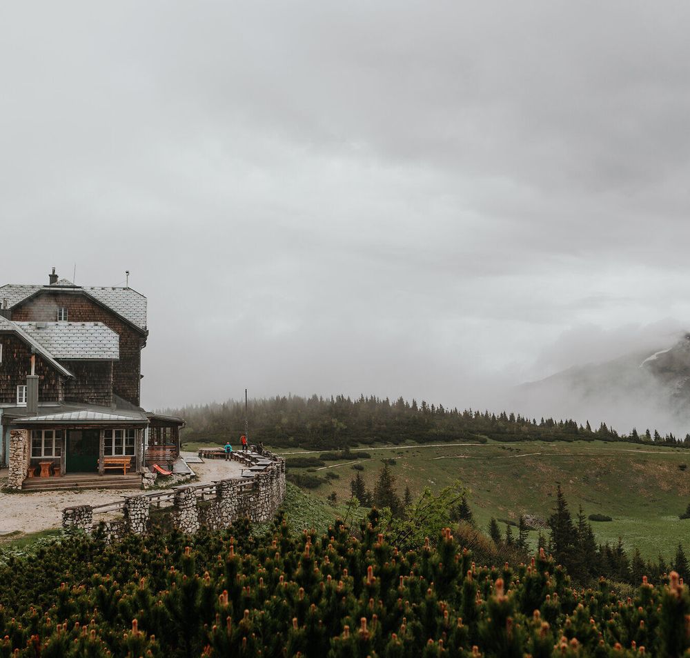 Umgeben von sanften Hügeln und dichten Wäldern strahlt die alpine Landschaft eine friedliche Ruhe aus. Die charmante Hütte lädt Wanderer ein, eine wohlverdiente Pause einzulegen und die atemberaubende Aussicht auf die umliegenden Berge zu genießen. Hier, wo die Natur in voller Pracht erblüht, wird jeder Schritt zum unvergesslichen Erlebnis.