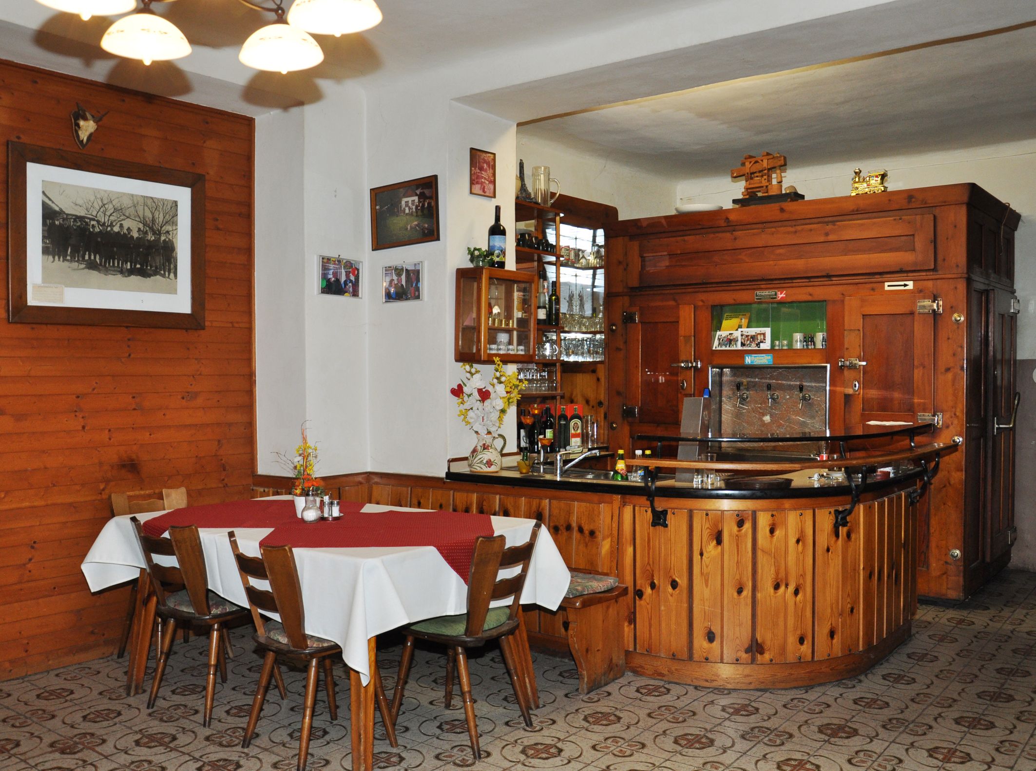 Innenansicht eines traditionellen Gasthofs mit Holzmöbeln und Bar.