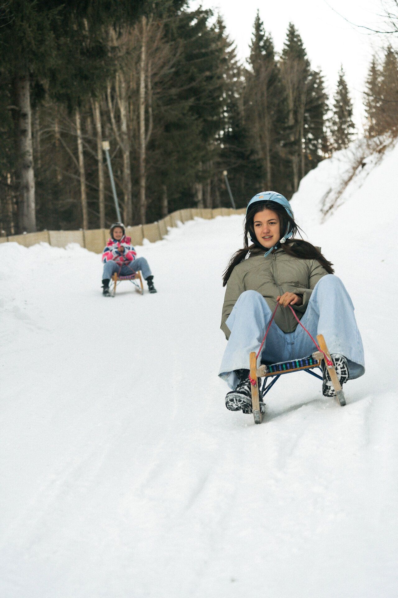 Zwei Frauen beim Rodeln auf einer verschneiten Rodelbahn am Semmering Hirschenkogel.