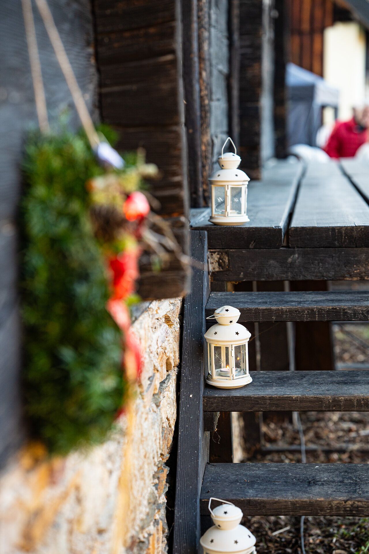 Holztreppe mit kleinen Laternen und winterlicher Dekoration vor einer Hütte.