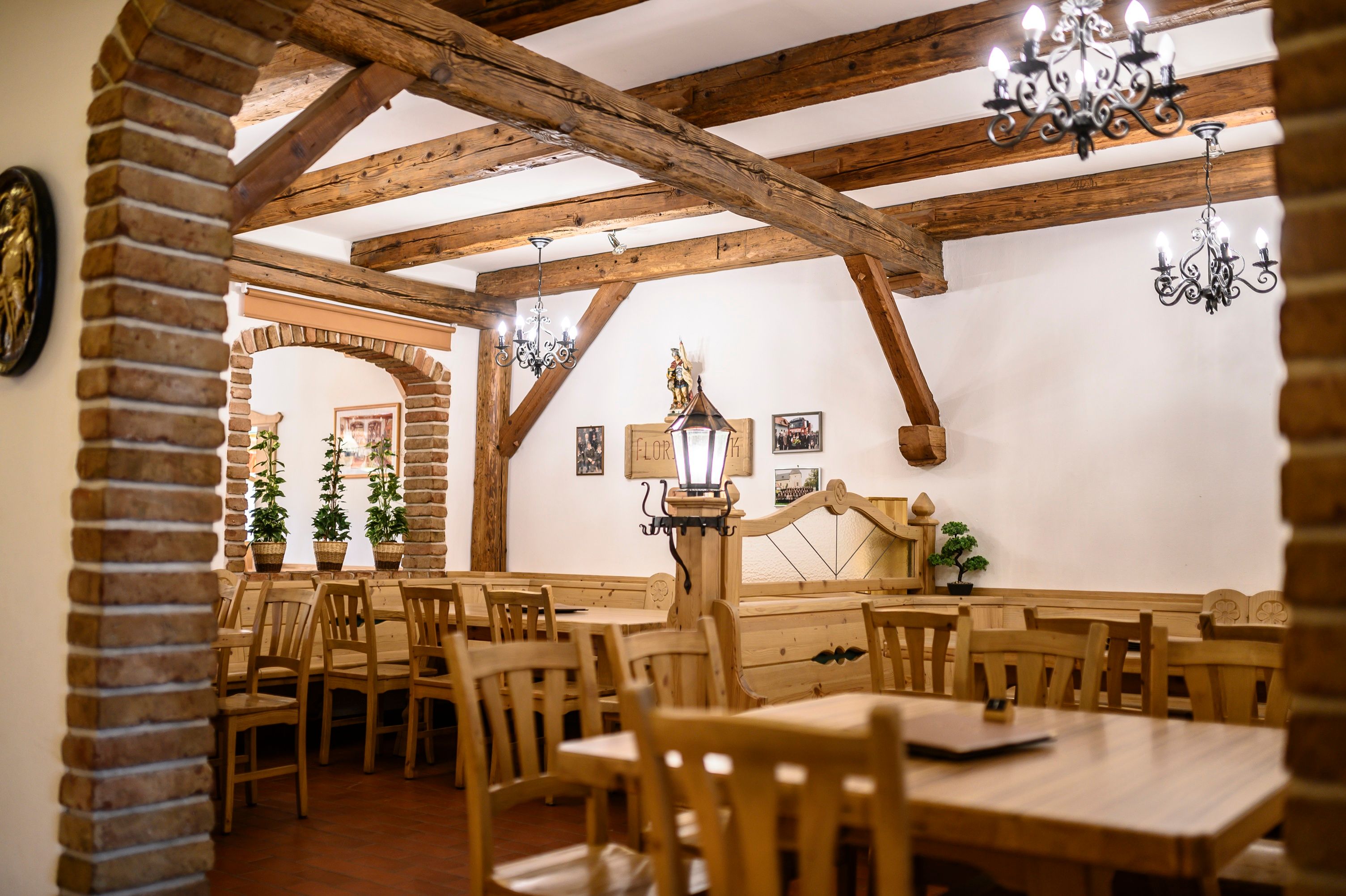 Innenansicht eines rustikalen Gastraums mit Holzmöbeln und Ziegelbögen.
