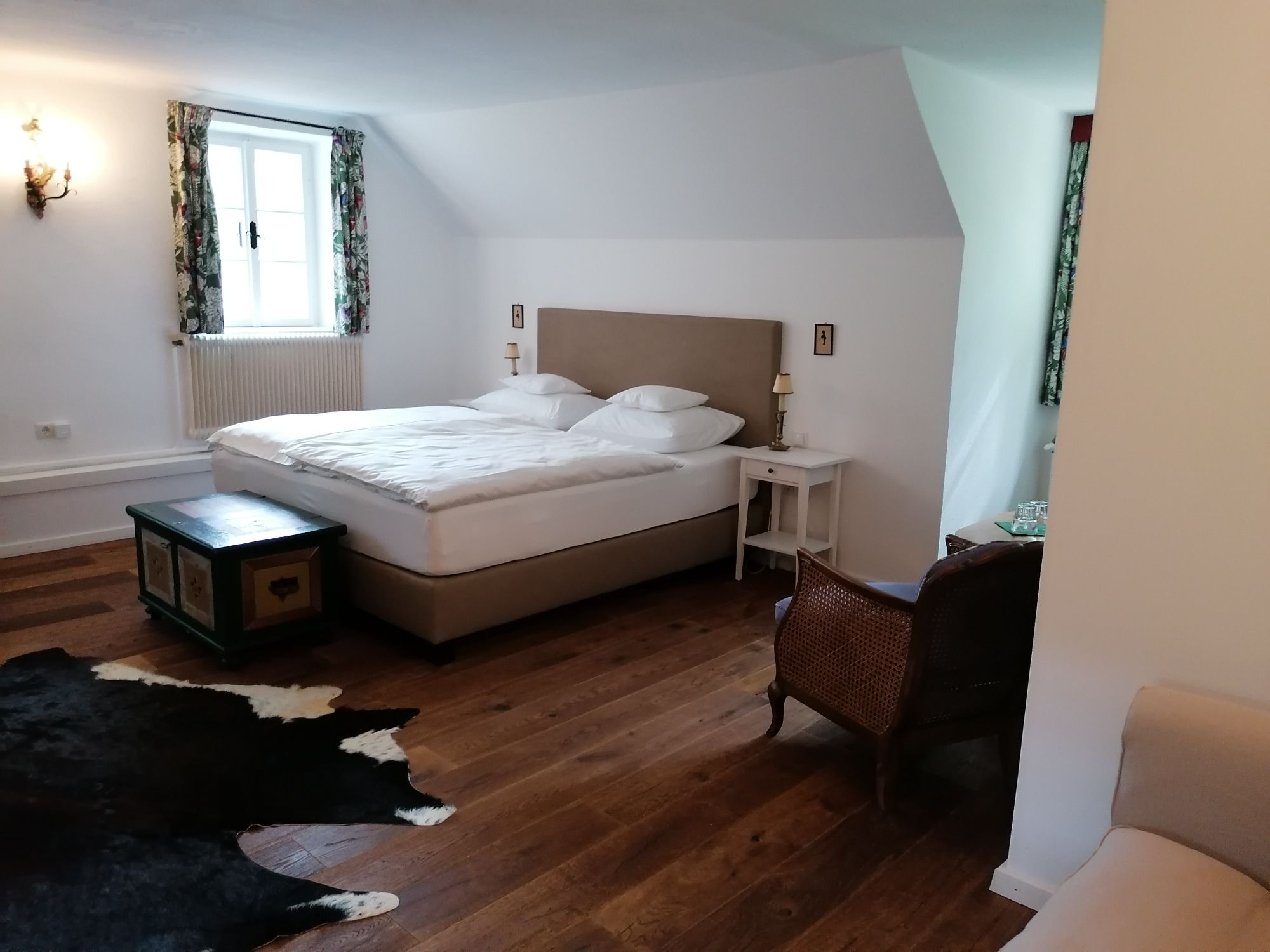 Gemütliches Schlafzimmer mit Doppelbett, Holzboden, Teppich und antiken Möbeln.