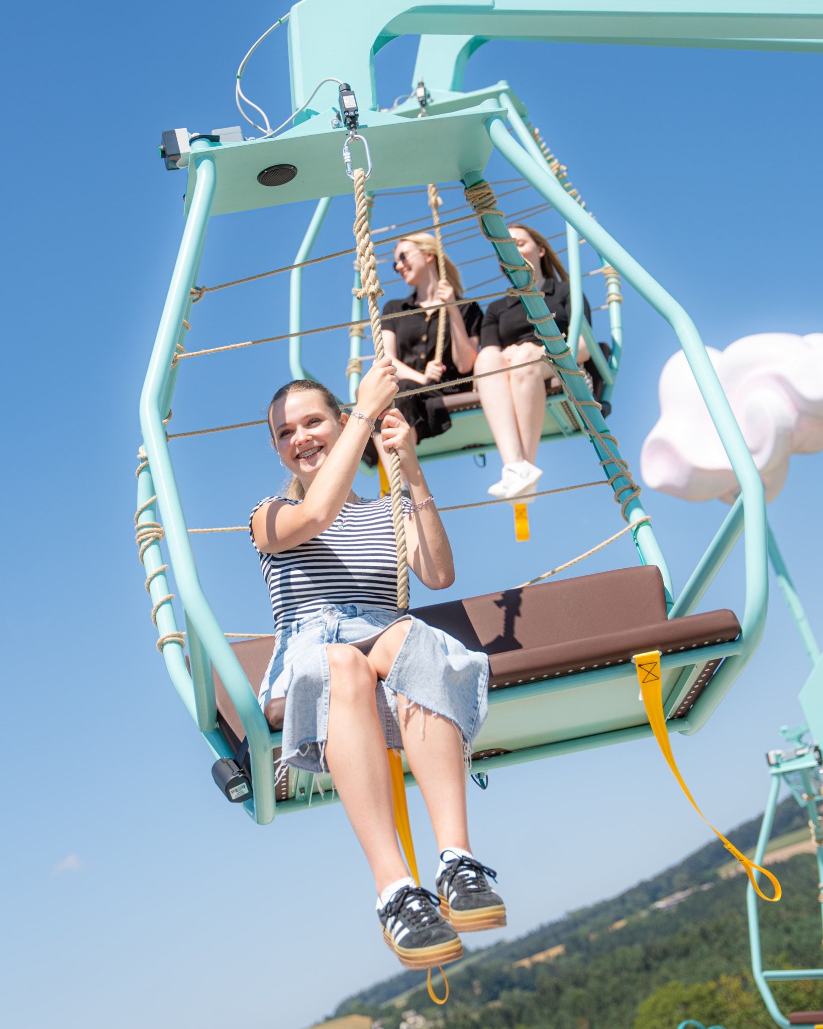 Eine junge Frau sitzt auf einem Sitz des Fahrgeschäfts Wolkenfänger im Eis-Greissler-Erlebnispark.