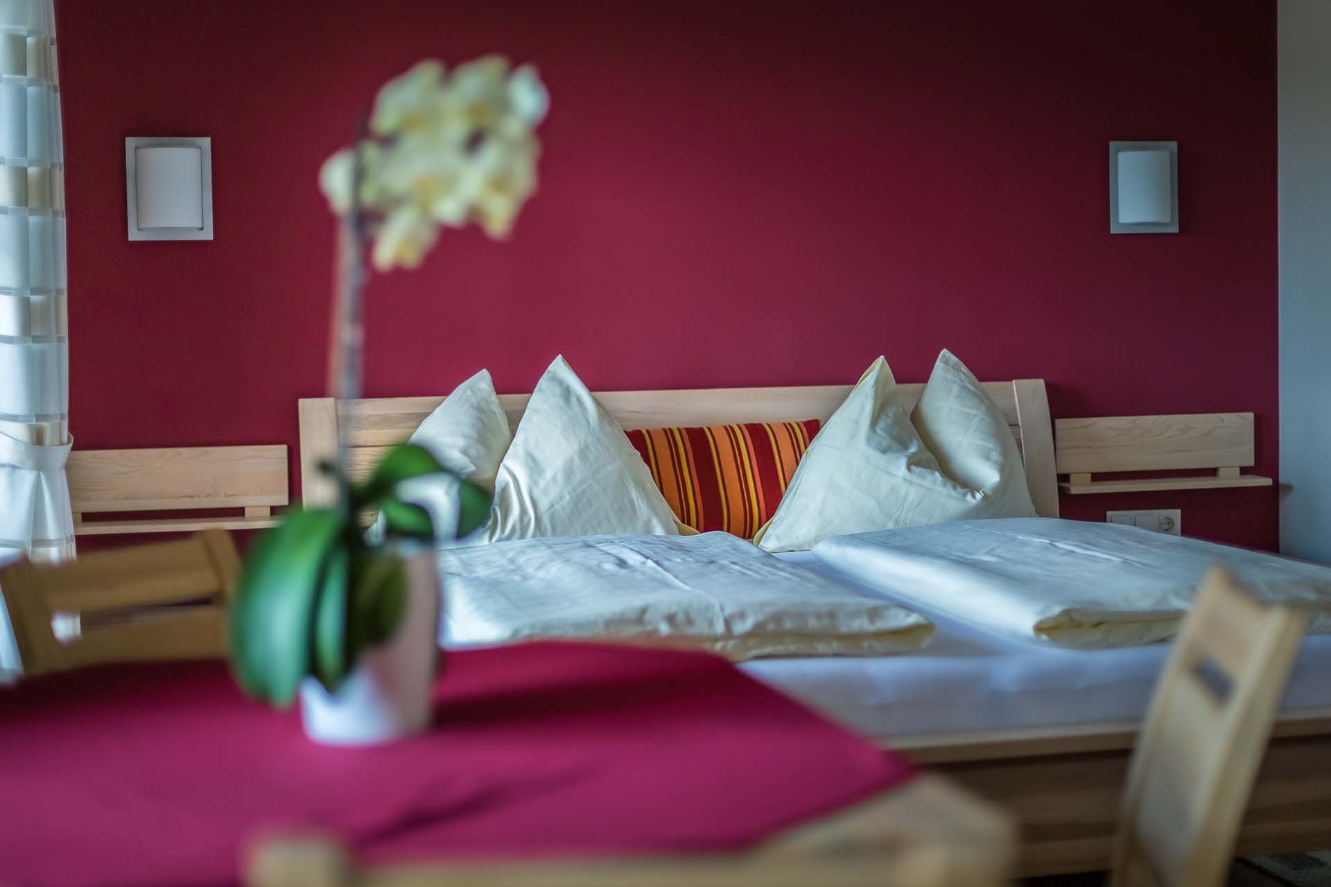 Gemütliches Schlafzimmer mit roter Wand, Holzbett und Kissen.