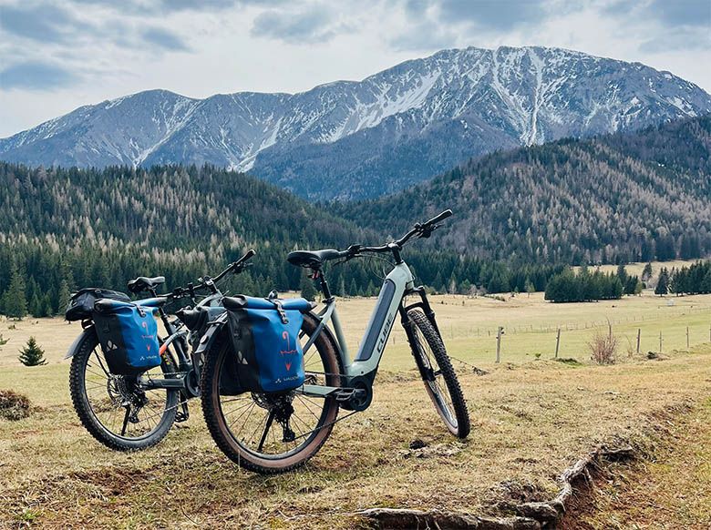 Two mountain bikes with blue bags in front of a mountain landscape in the Schneebergland.