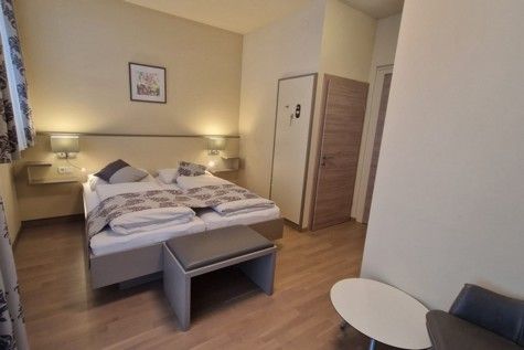 Hotelzimmer mit Doppelbett, Holzboden und moderner Einrichtung.