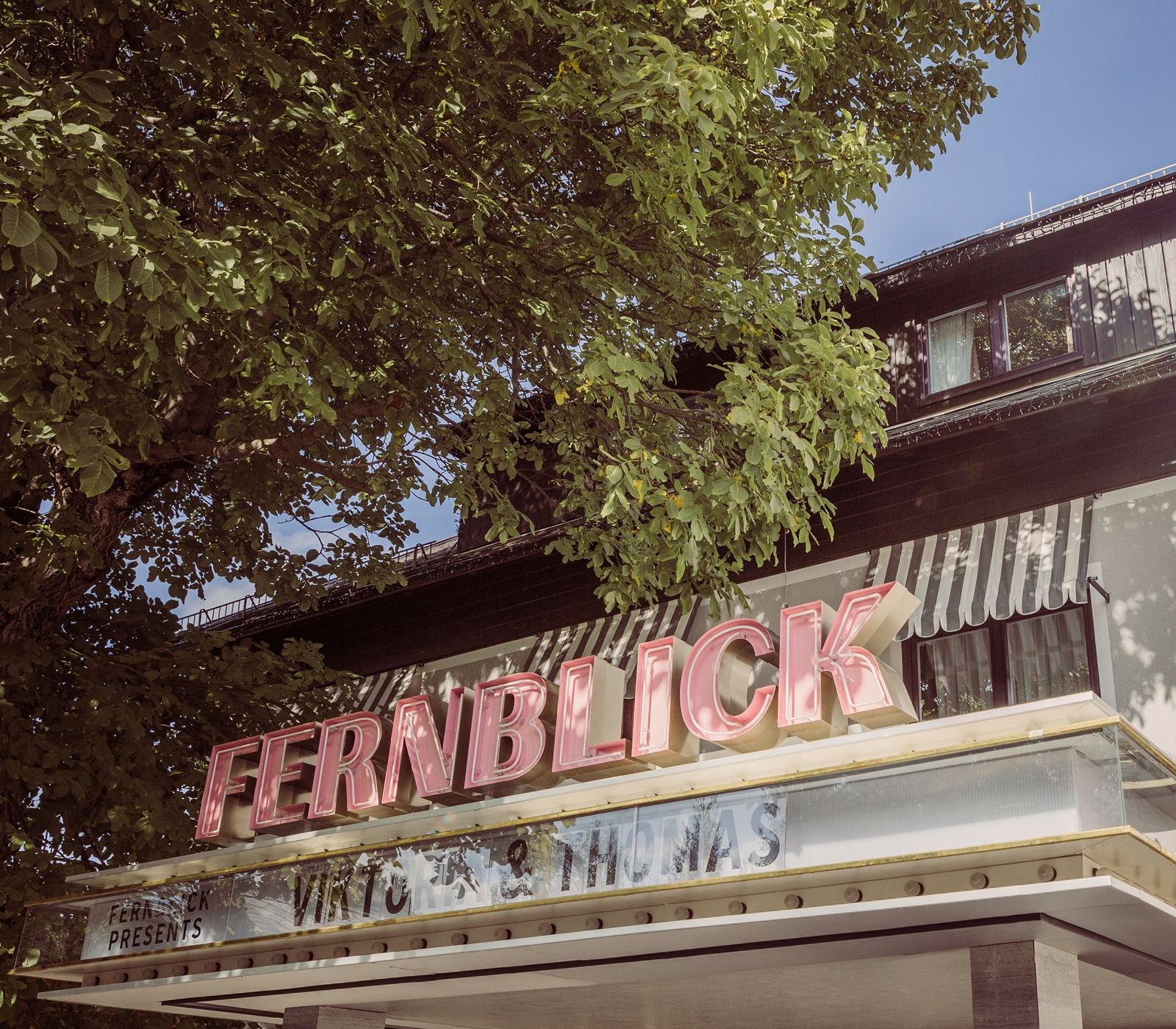 Gebäude mit dem Schriftzug 'FERNBLICK' und Bäumen im Vordergrund.