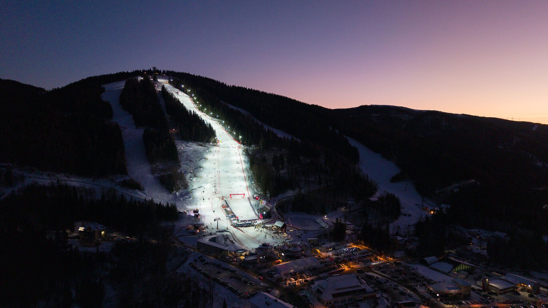 Luftaufnahme der beleuchteten Skipisten am Semmering Hirschenkogel in der Abenddämmerung.