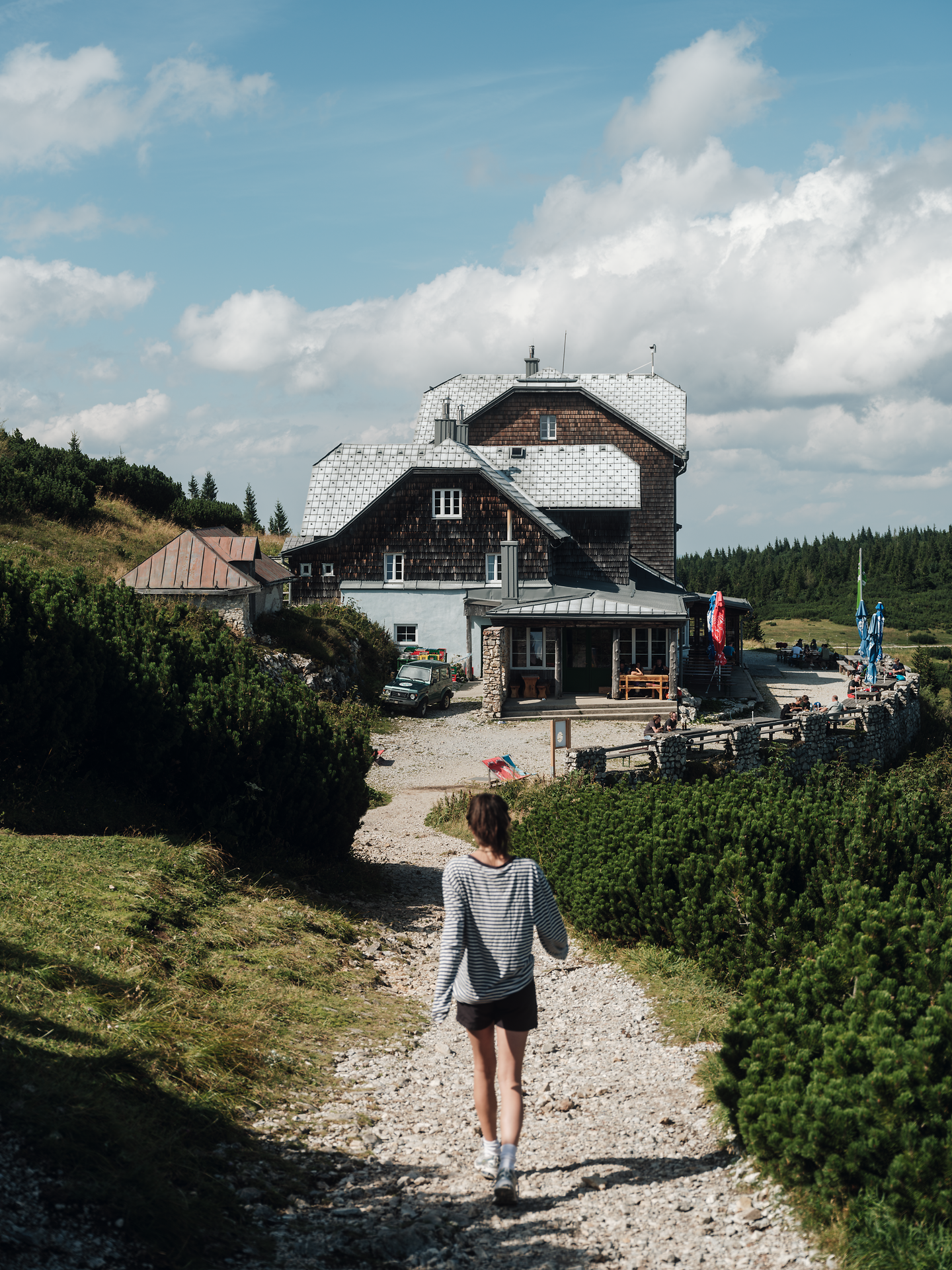 Ein malerischer Weg führt durch die sanften Hügel, umgeben von üppigem Grün und dem Duft der frischen Bergluft. Die charmante Hütte am Ende des Pfades lädt Wanderer ein, eine wohlverdiente Pause einzulegen und die atemberaubende Aussicht zu genießen.