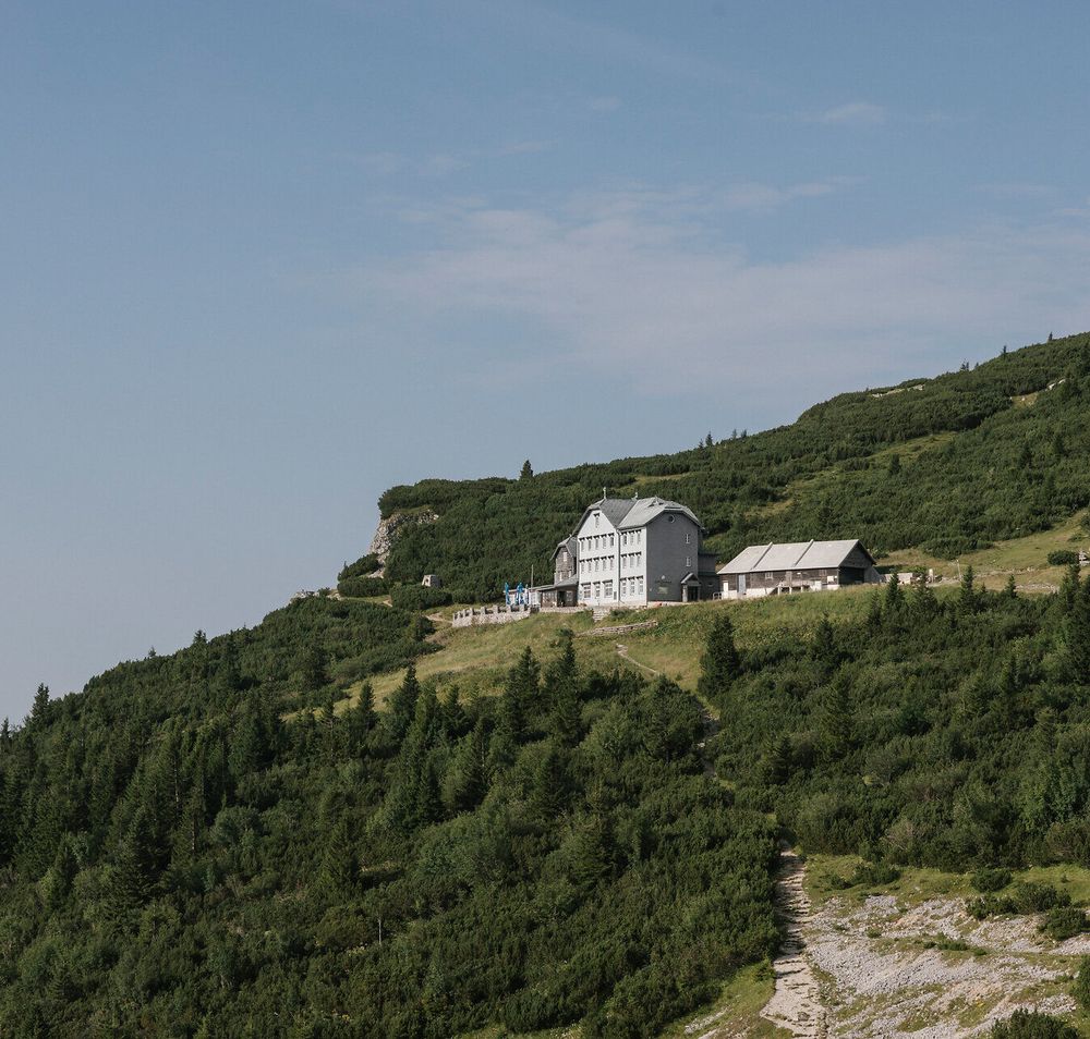 A panoramic view of the Ottohaus on the Rax, nestled among forested mountain slopes