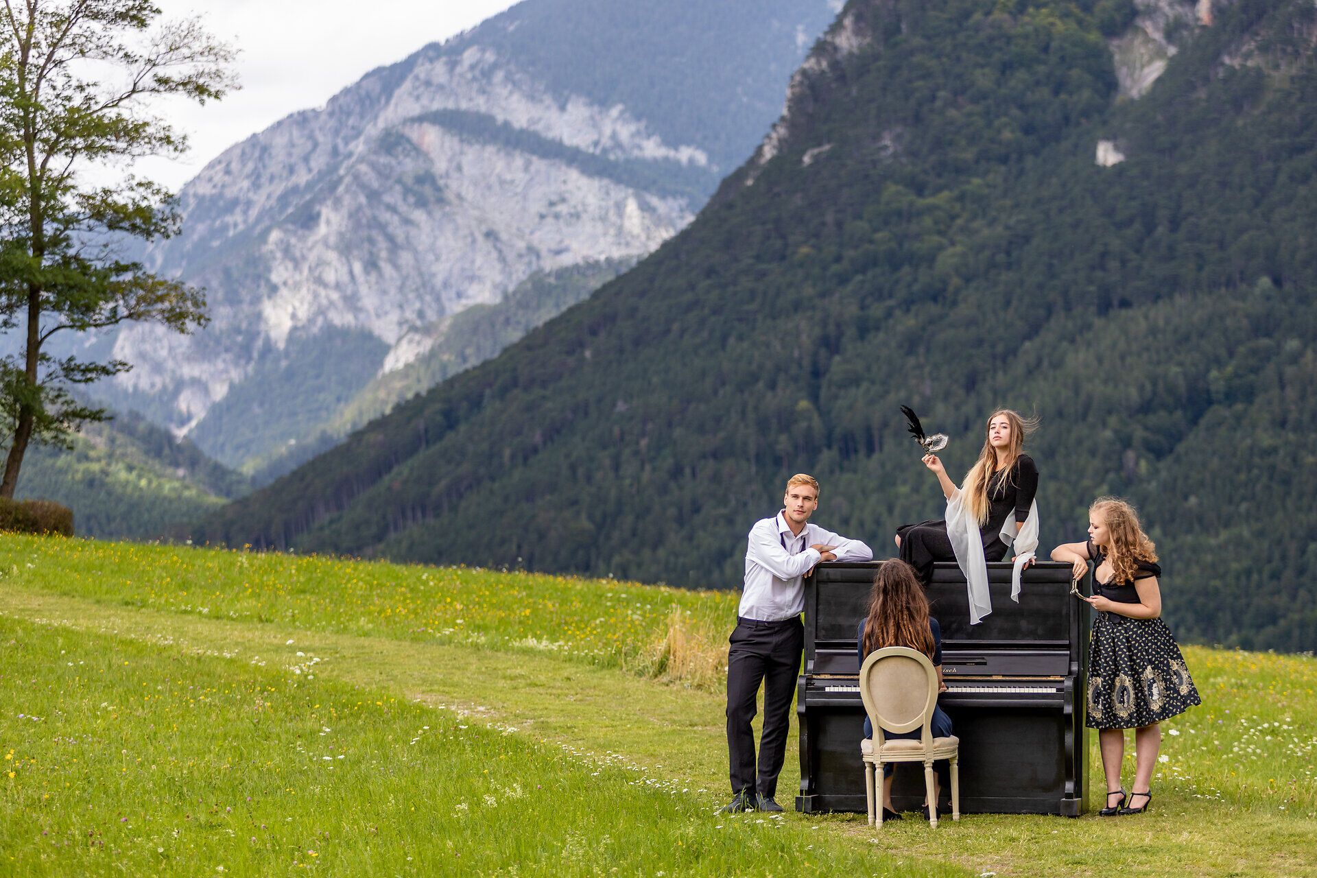 Eine Schauspielgruppe posiert mit Klavier und Masken vor der Kulisse der Rax.