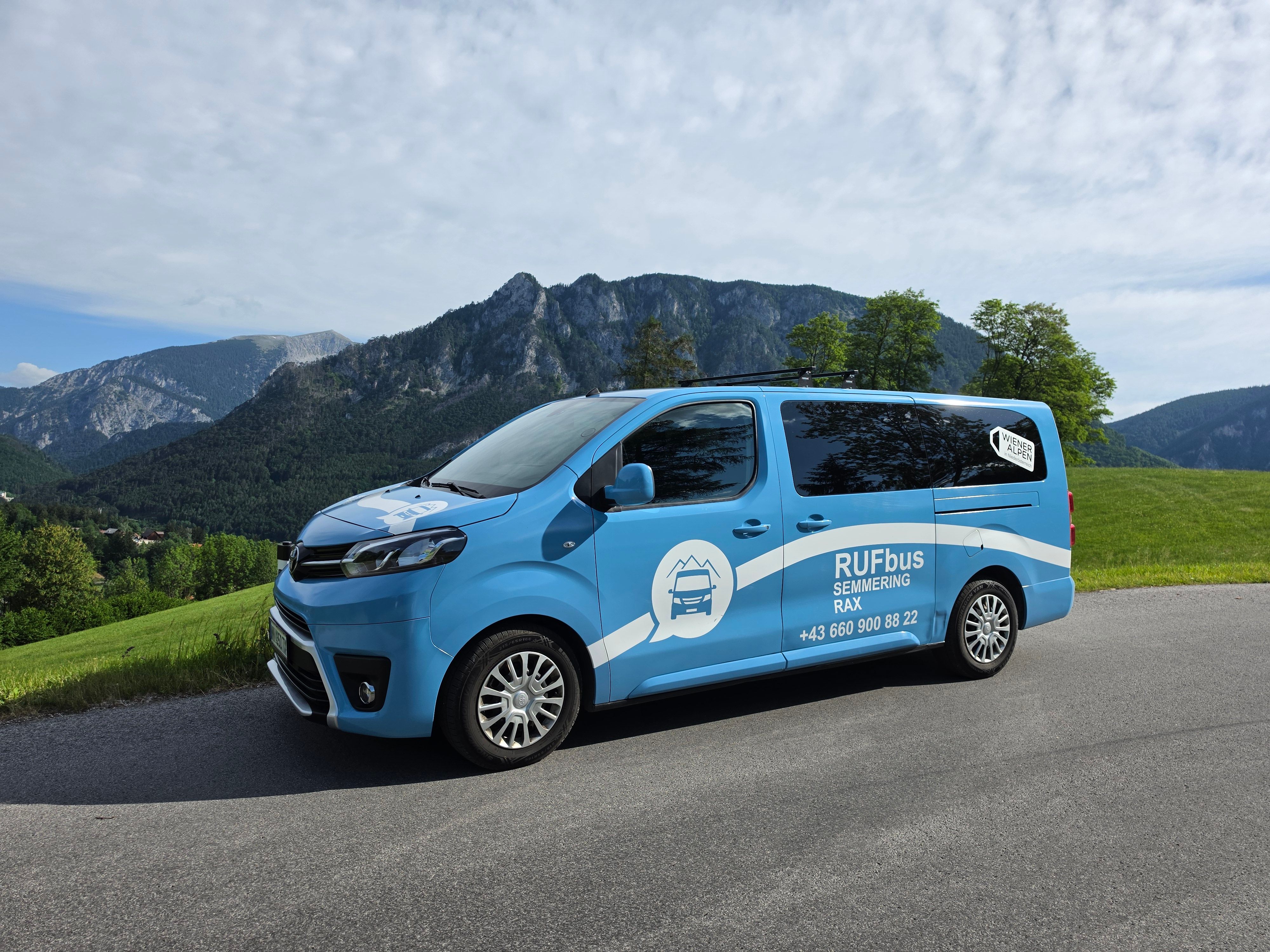 Ein Sammeltaxi steht auf einer Straße vor einer Berglandschaft.