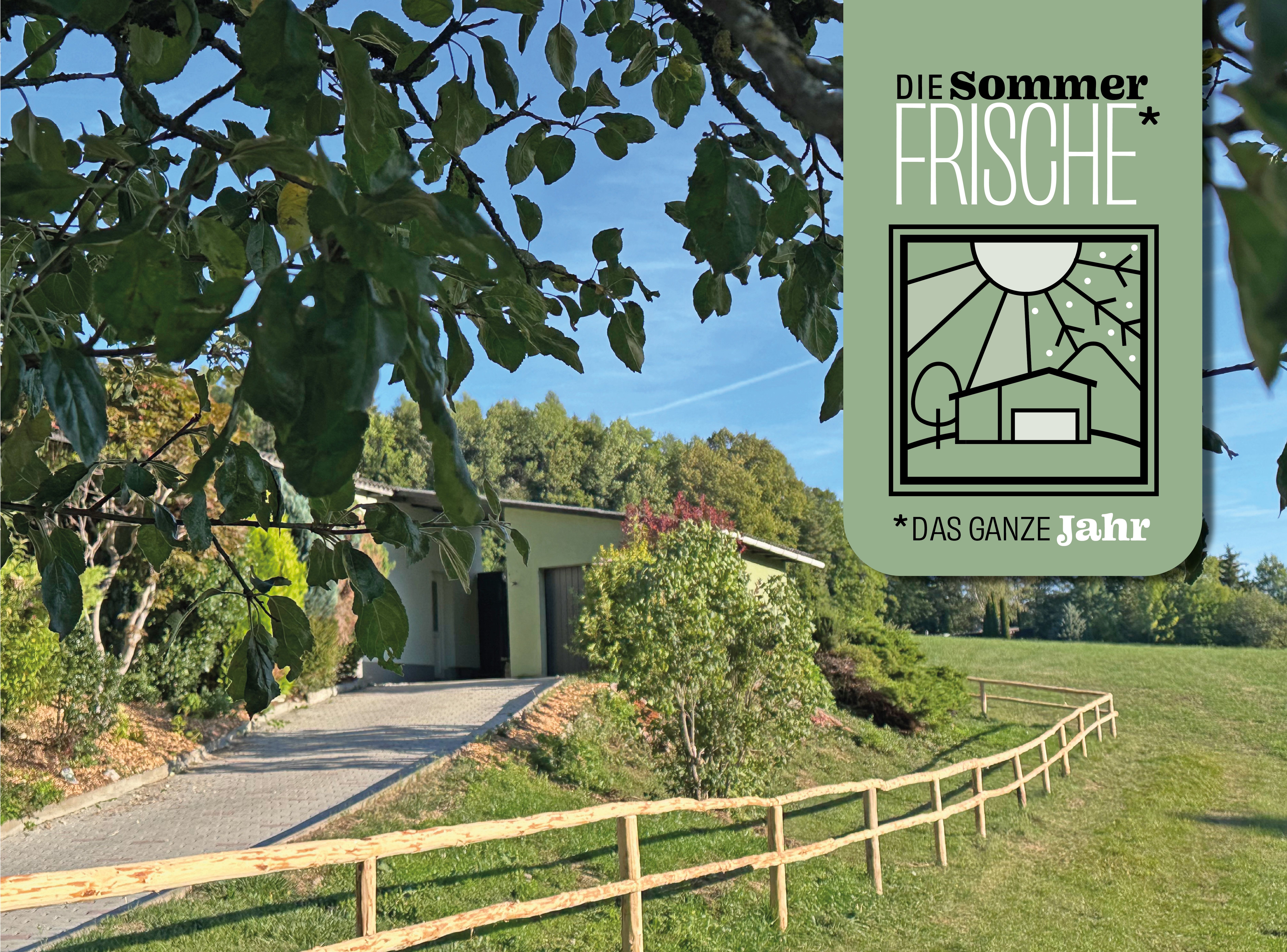 Landschaft mit Weg, Wiese, Bäumen und einem kleinen Gebäude; oben rechts ein grünes Plakat mit der Aufschrift „Die Sommerfrische – das ganze Jahr“.