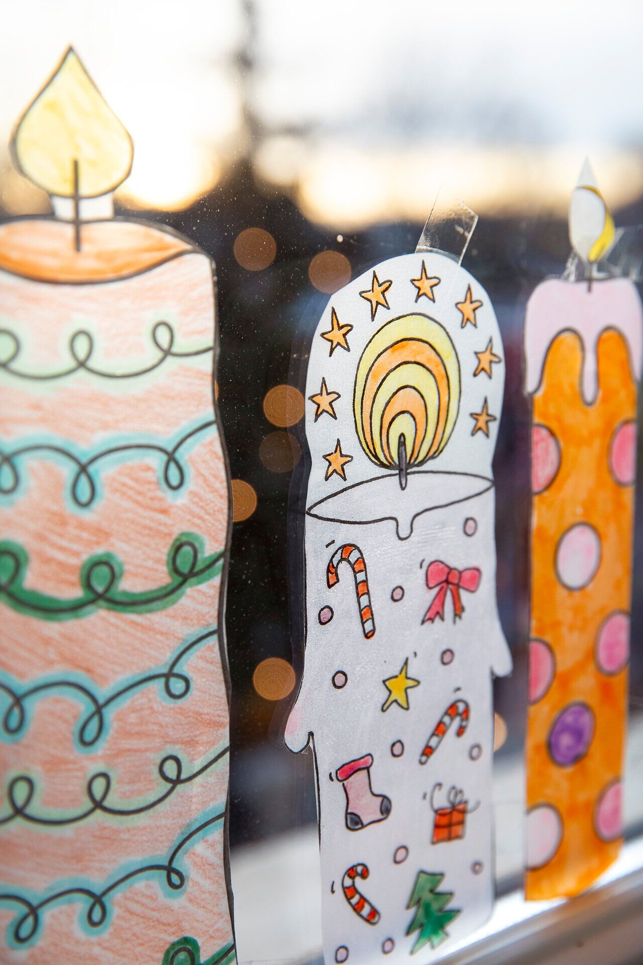 Detailaufnahme bunter, handbemalter Kerzen mit weihnachtlichen Motiven.