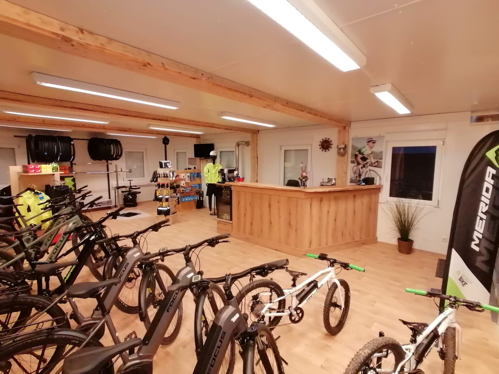 Innenansicht eines Fahrradverleihs mit E-Bikes und Zubehör.