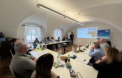 Workshop Teilnehmer sitzen an Tischen während ein Mann einen Vortrag hält.