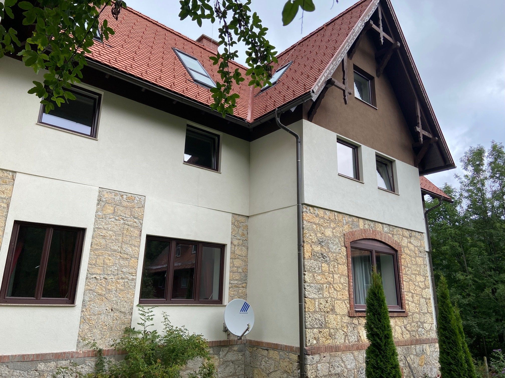 Side view of a villa with a red roof and stone masonry.