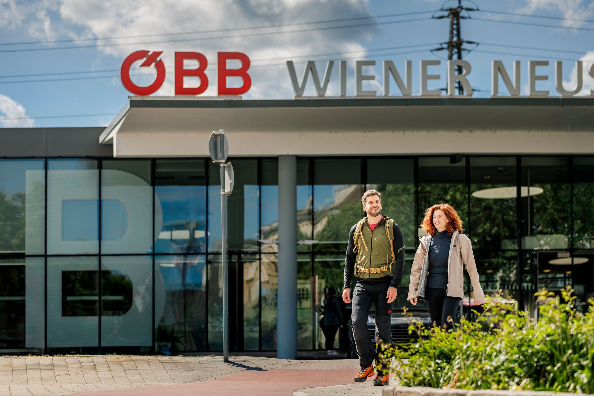 Ein Frau und ein Mann gehen vor dem Bahnhof Wiener Neustadt.