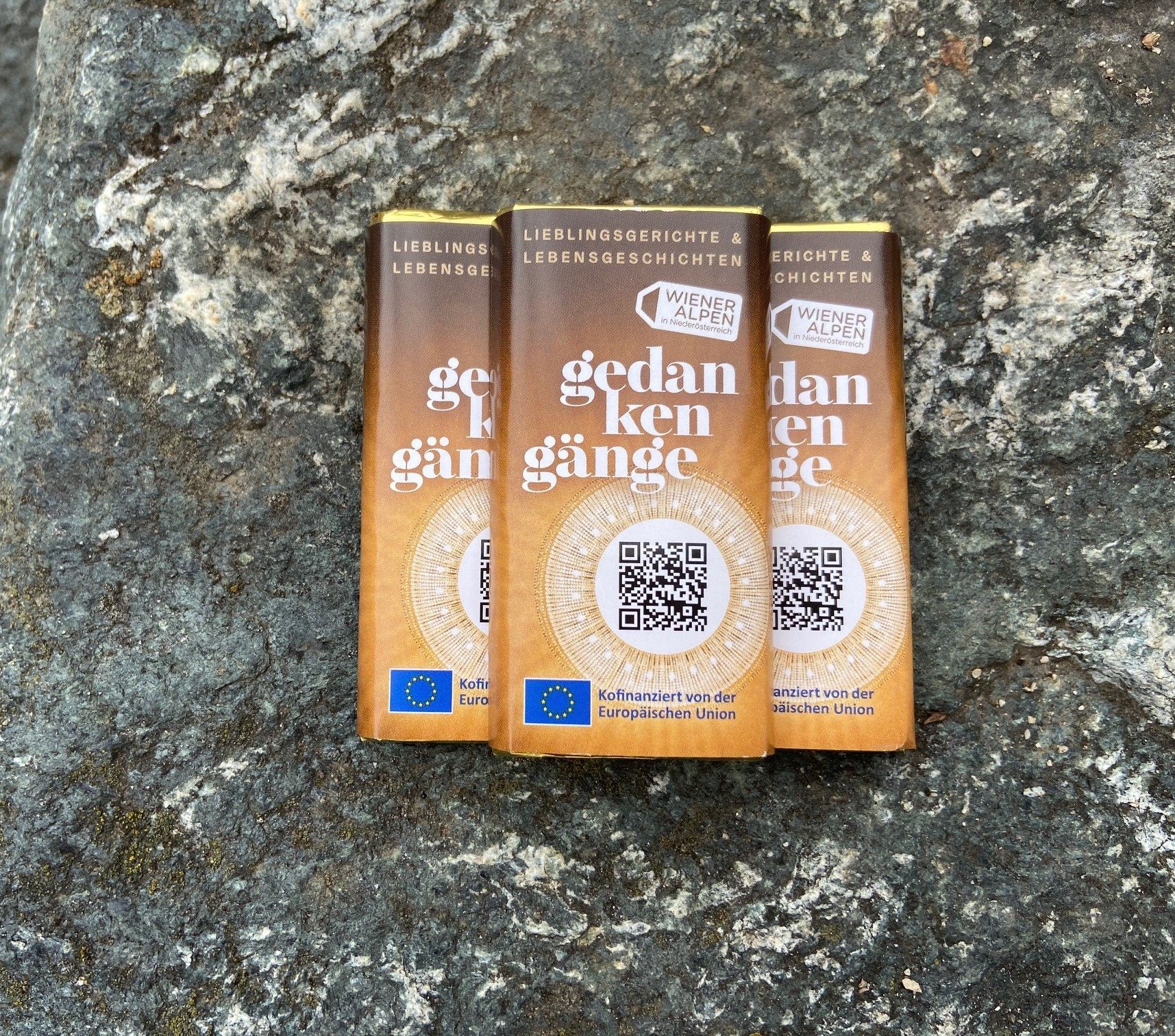 Drei kleine Lindt Schokotafeln mit mit Gedanken-Gänge Branding liegen auf einem Steinhintergrund