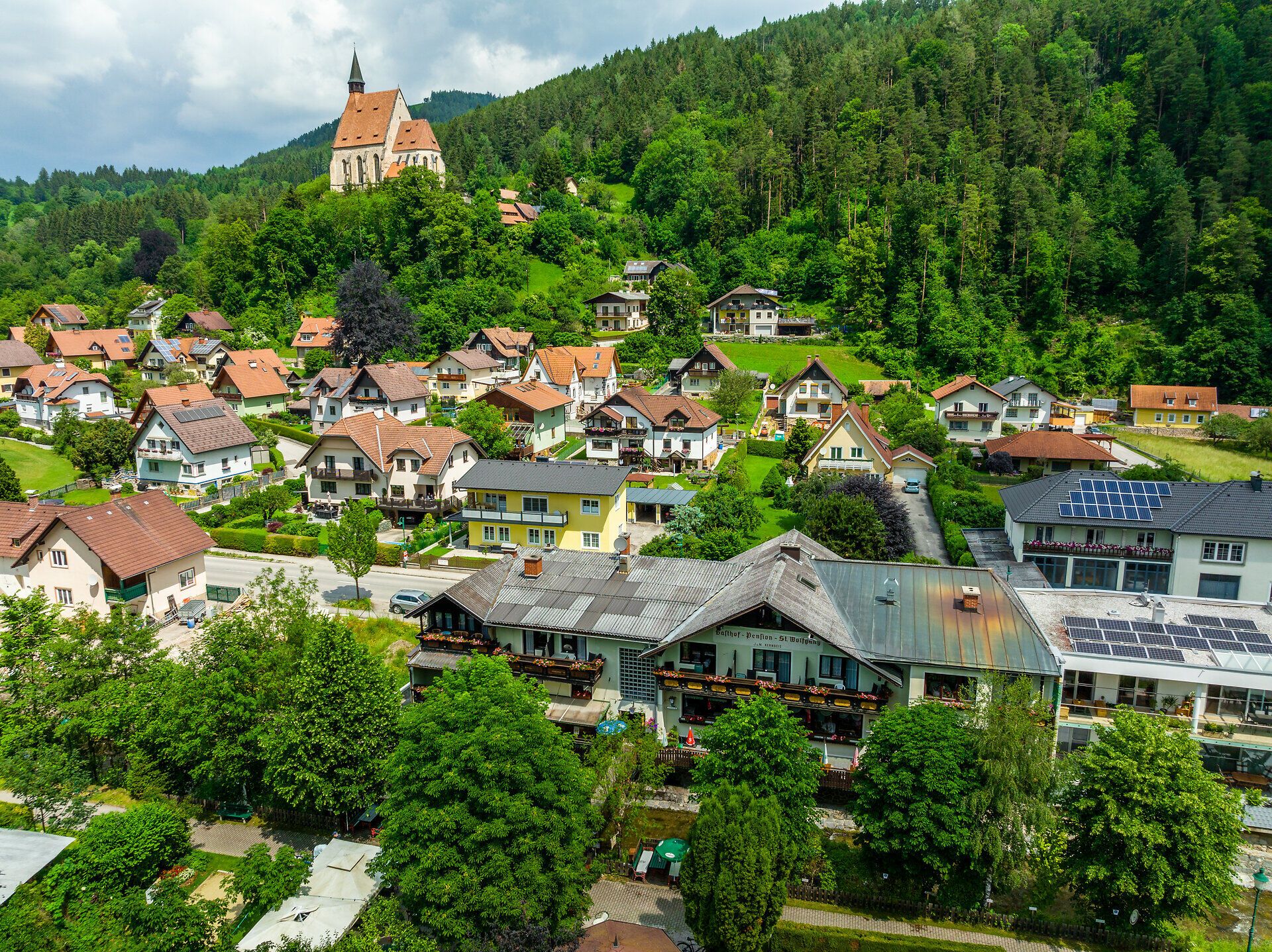 Auf der Luftansicht ist im Vordergrund der Gasthof Pension St. Wolfgang zu erkennen, im Hintergrund Teile von Kirchberg am Wechsel inklusive der Wolfgangskirche.