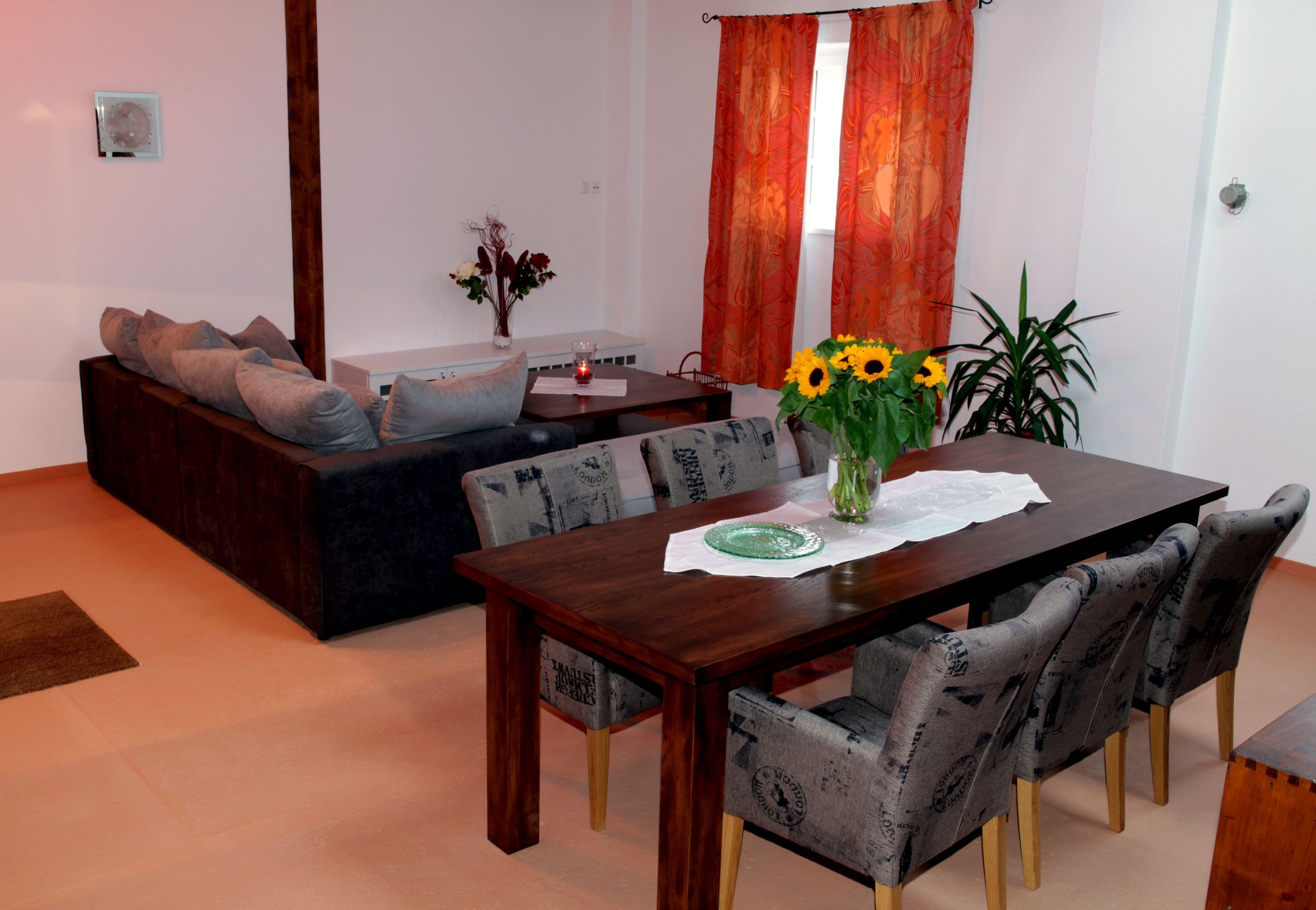 Wohn- und Essbereich in einem Loft mit Holztisch, Stühlen, Sofa und Dekorationen.