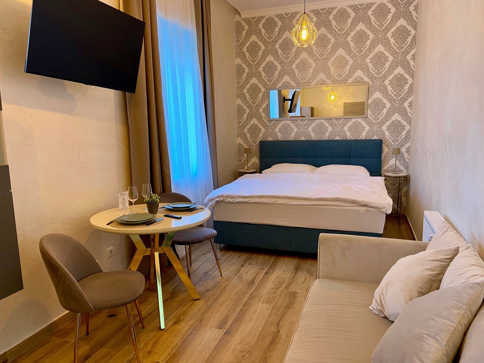 Ein gemütliches Hotelzimmer mit Doppelbett, kleinem Esstisch und Sofa.