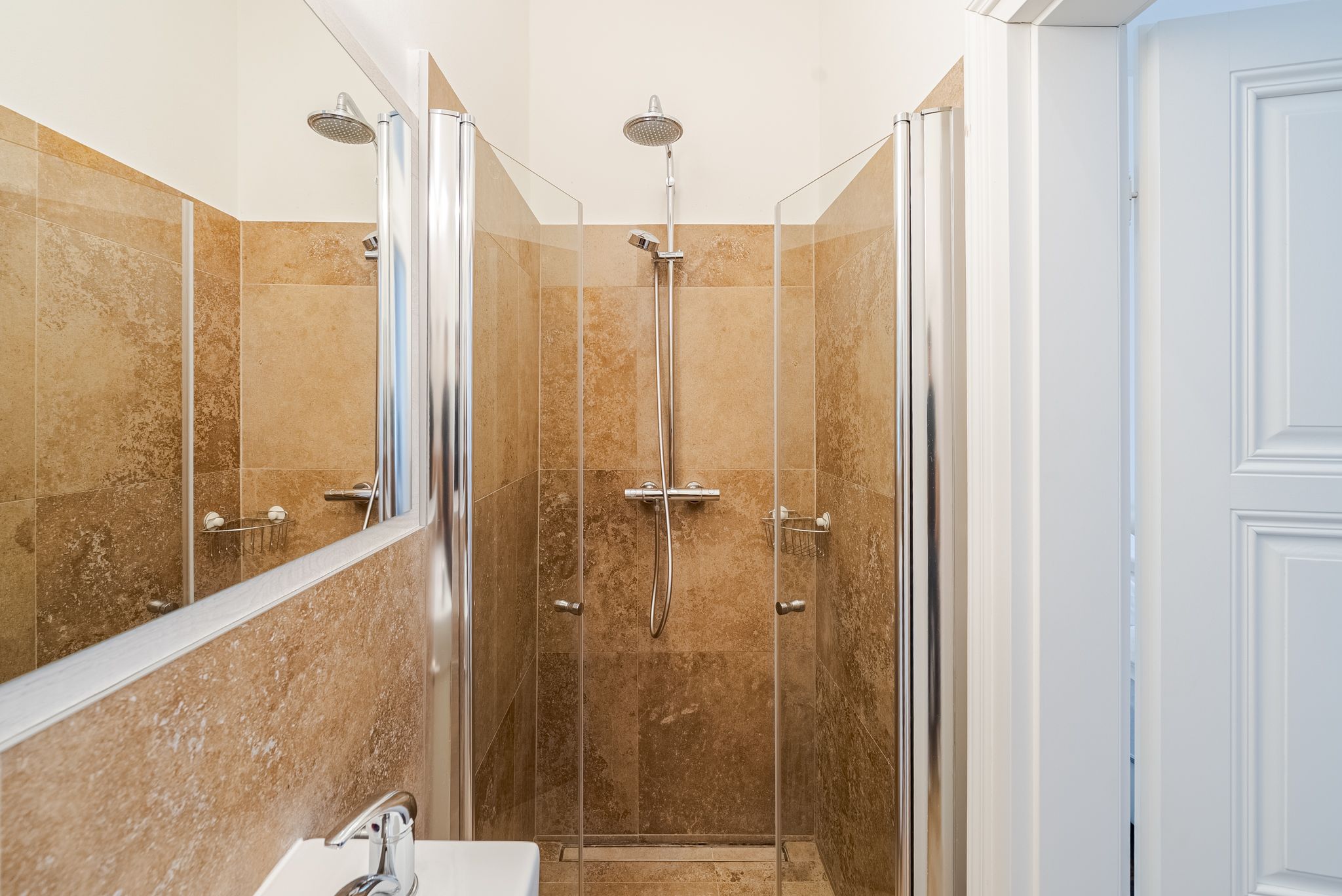 Moderne Dusche mit Glaswänden und beigen Fliesen.