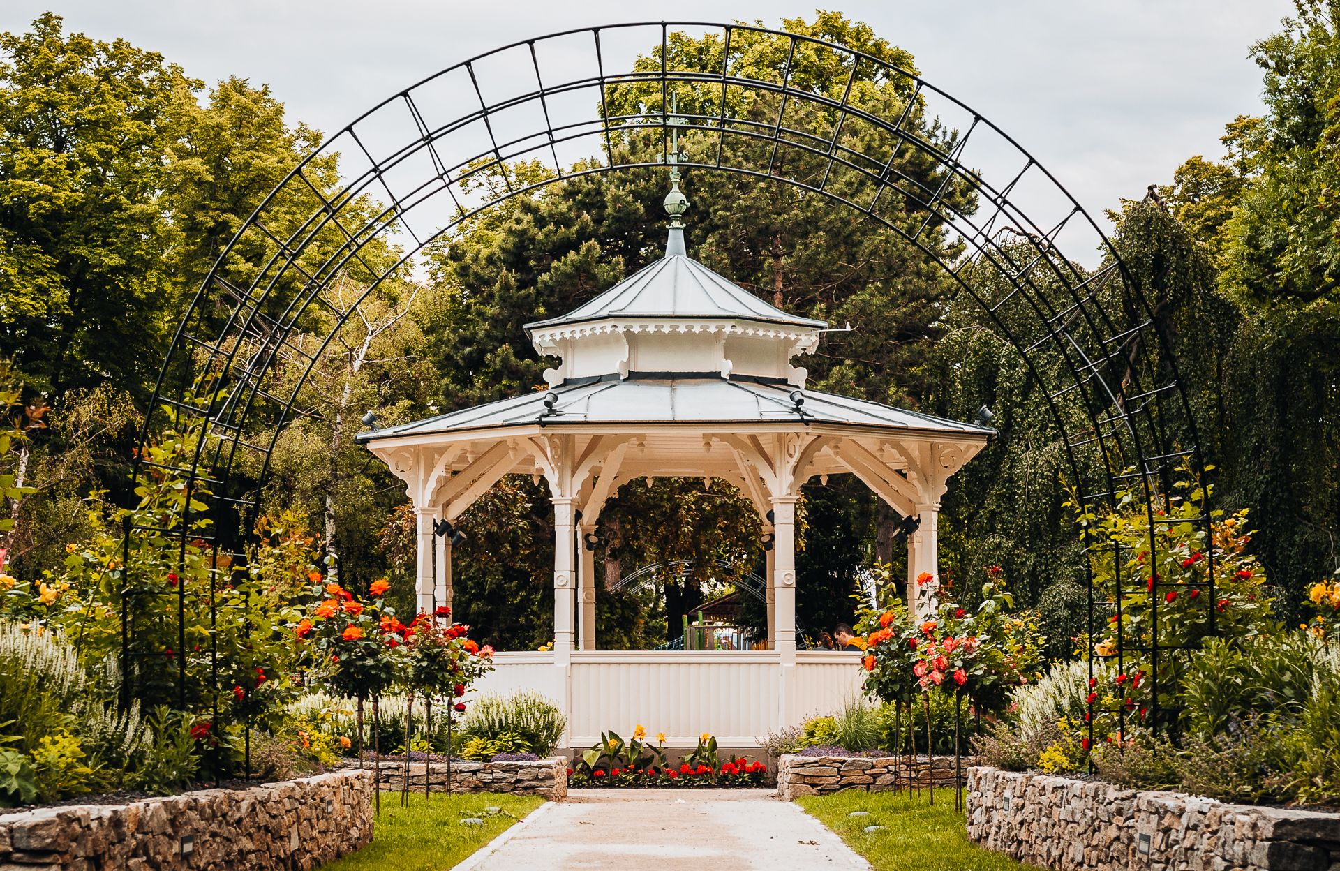 Weißer Pavillon im Stadtpark von Wiener Neustadt, umgeben von Pflanzen.