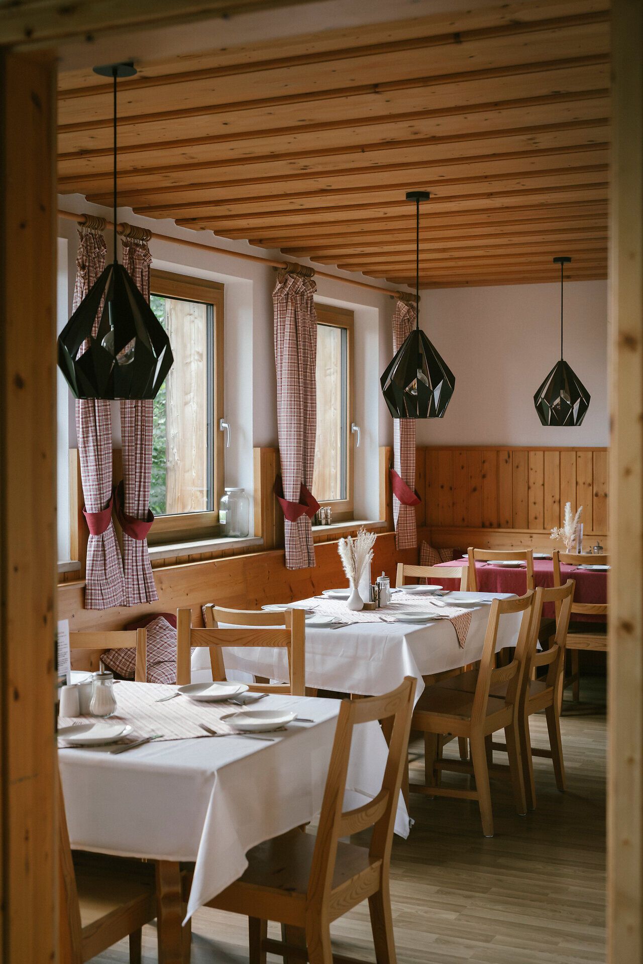 Cozy dining room at the Haltestelle Baumgartner mountain hut, with set tables and a wood-paneled interior