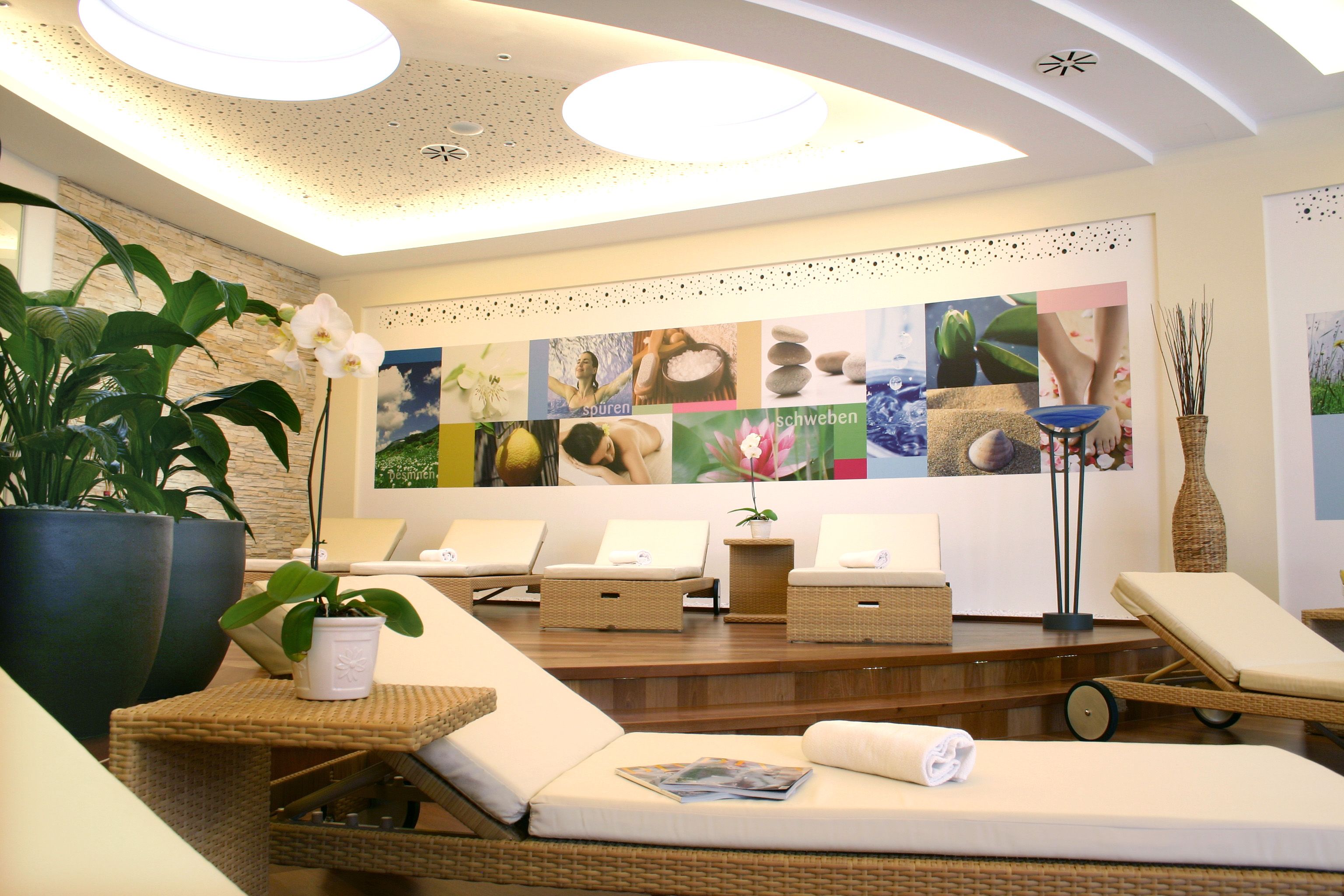 Ein eleganter Wellnessbereich mit Liegestühlen, Pflanzen und beruhigender Wanddekoration.