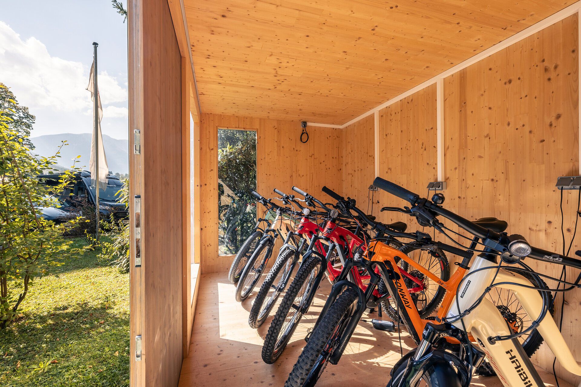Viele verschiedene Räder parken und laden im Radabstellraum beim Hotel Schneeberghof