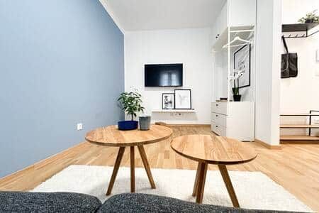 Living room with gray-blue walls, TV, living room table and shelves.
