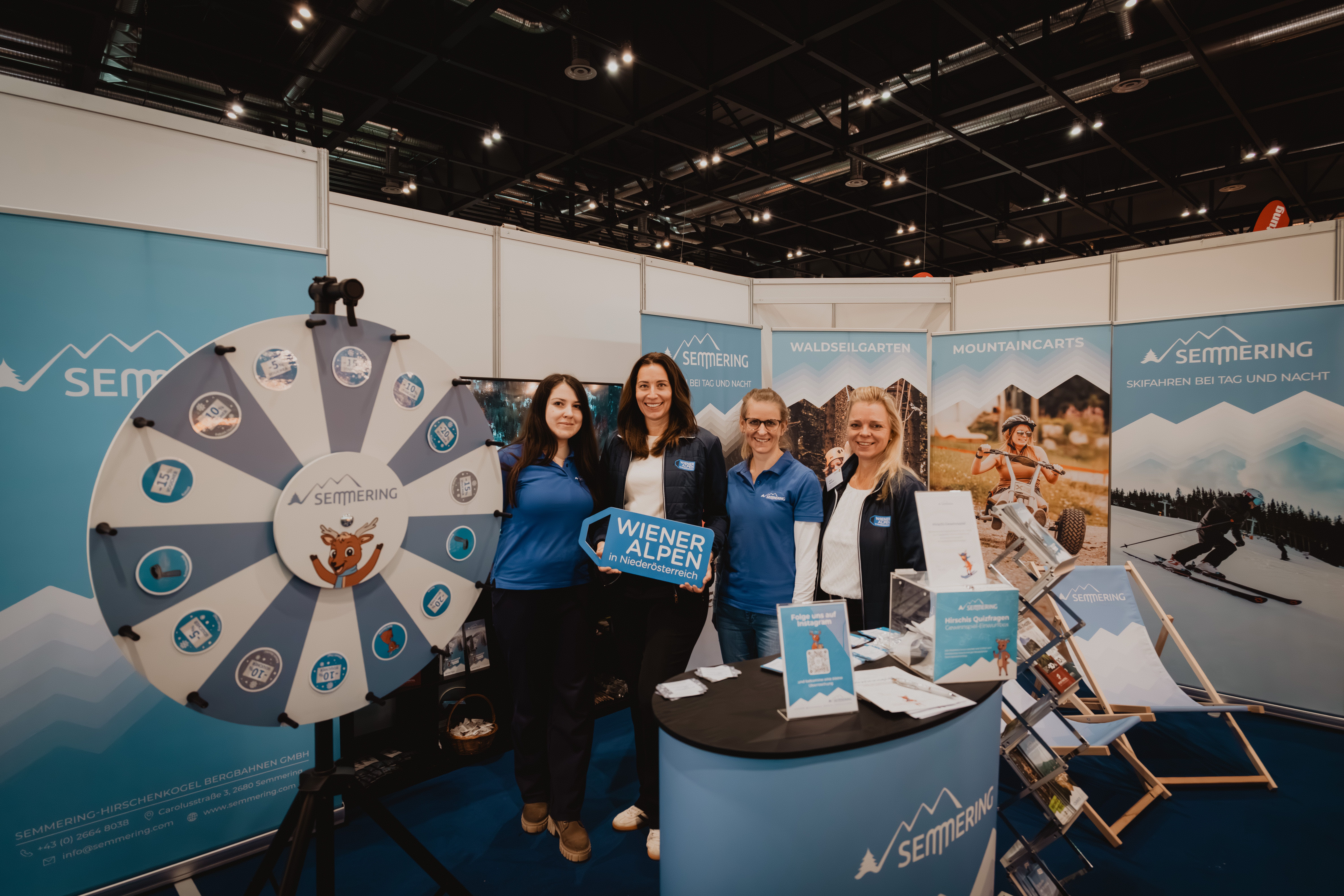 Eine Gruppe vor dem Glücksrad mit dem Wiener Alpen Schild