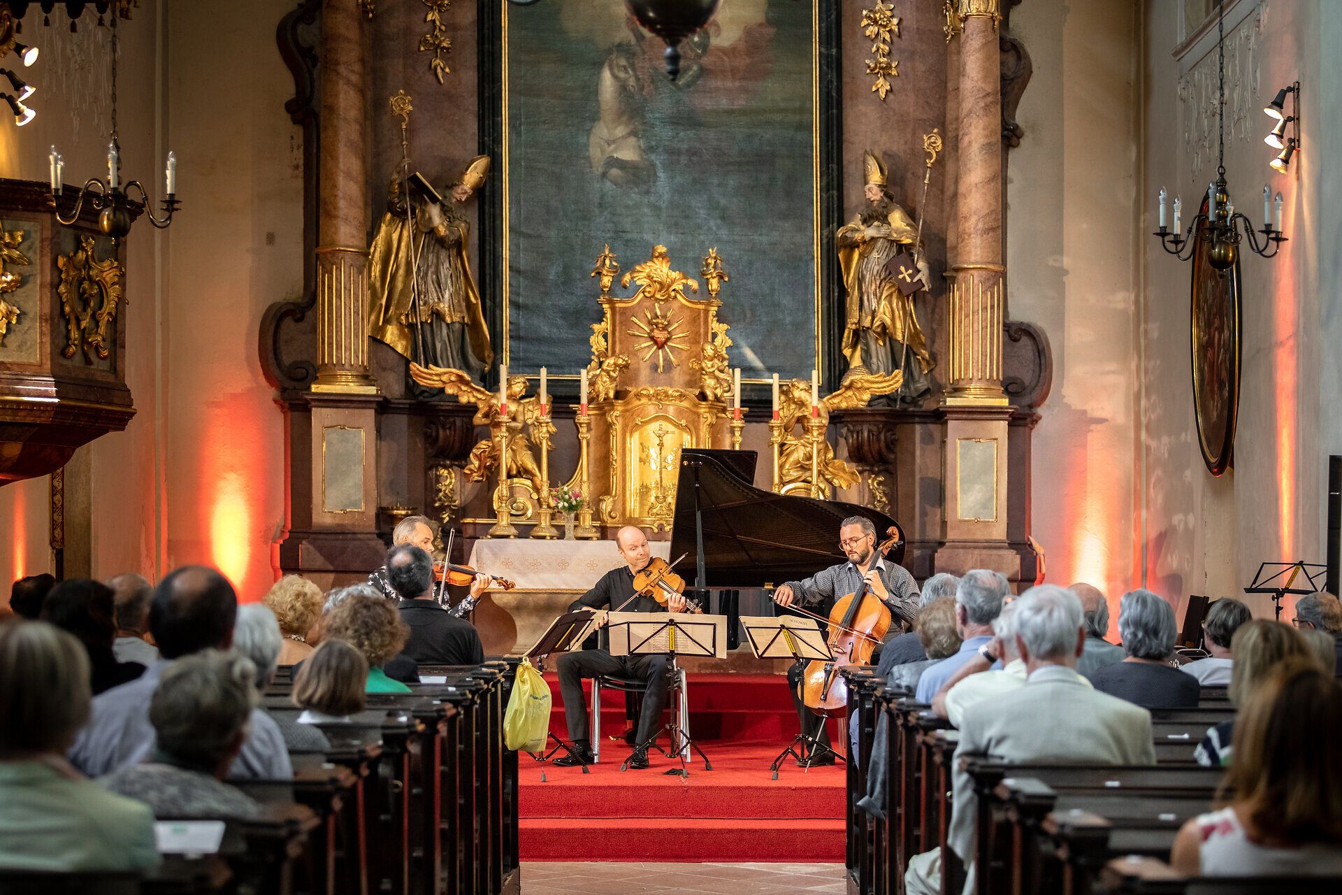 Drei Musiker spielen ein Konzert vor einem Publikum in einer Kirche.