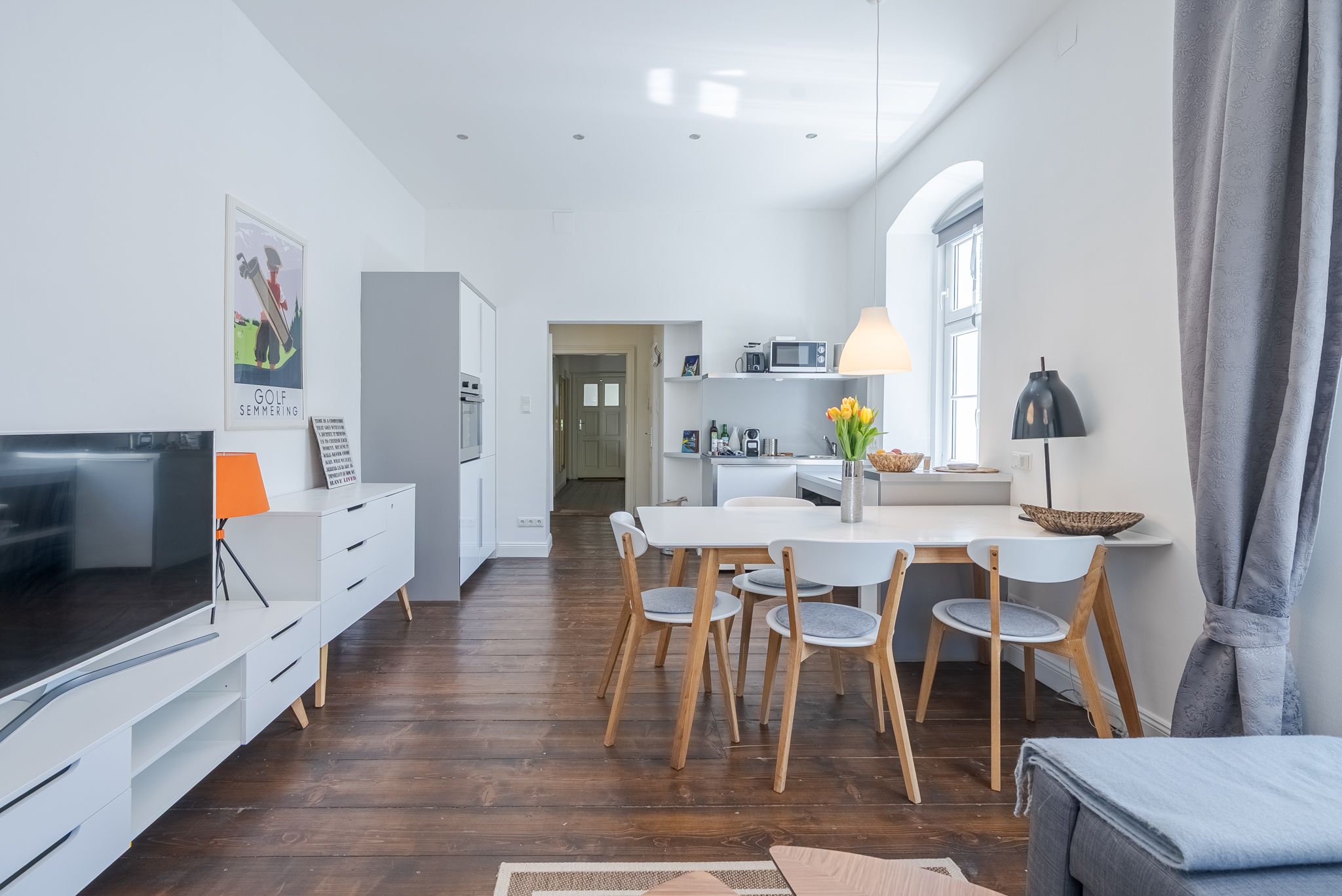 Modern eingerichtetes Wohnzimmer mit Esstisch, Stühlen und Küchenzeile.