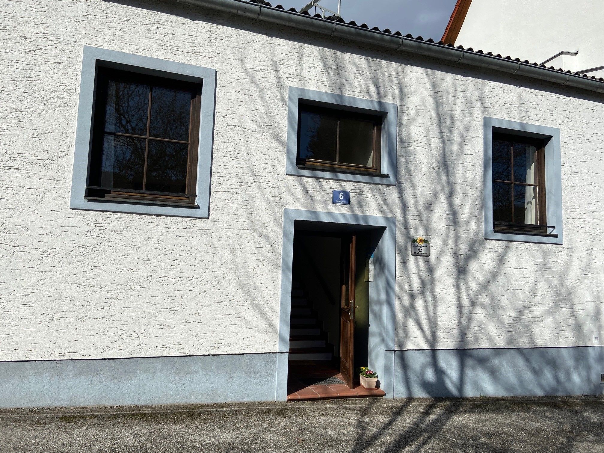 Eingang eines weißen Gebäudes mit blauen Fensterrahmen und Türrahmen.