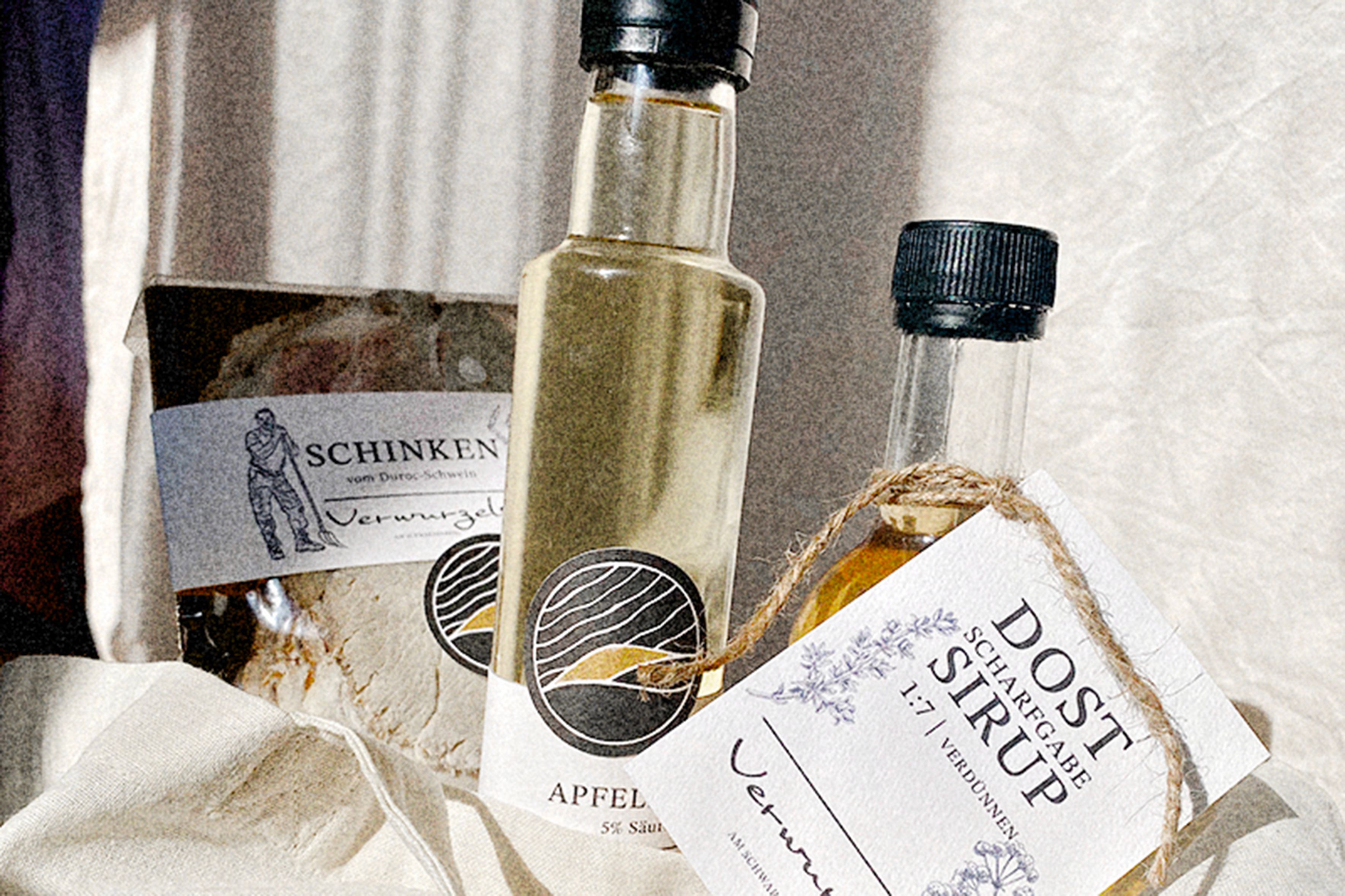 Nahaufnahme von Schinken, Apfelessig und Sirup mit Etiketten auf einem Tuch.