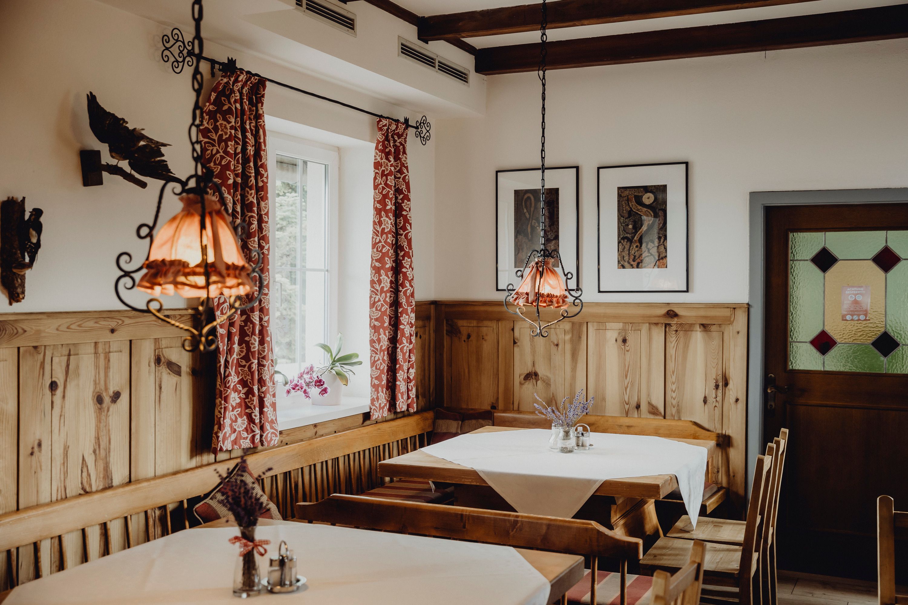 Cozy dining room with wooden furniture, red curtains and decorative lamps.