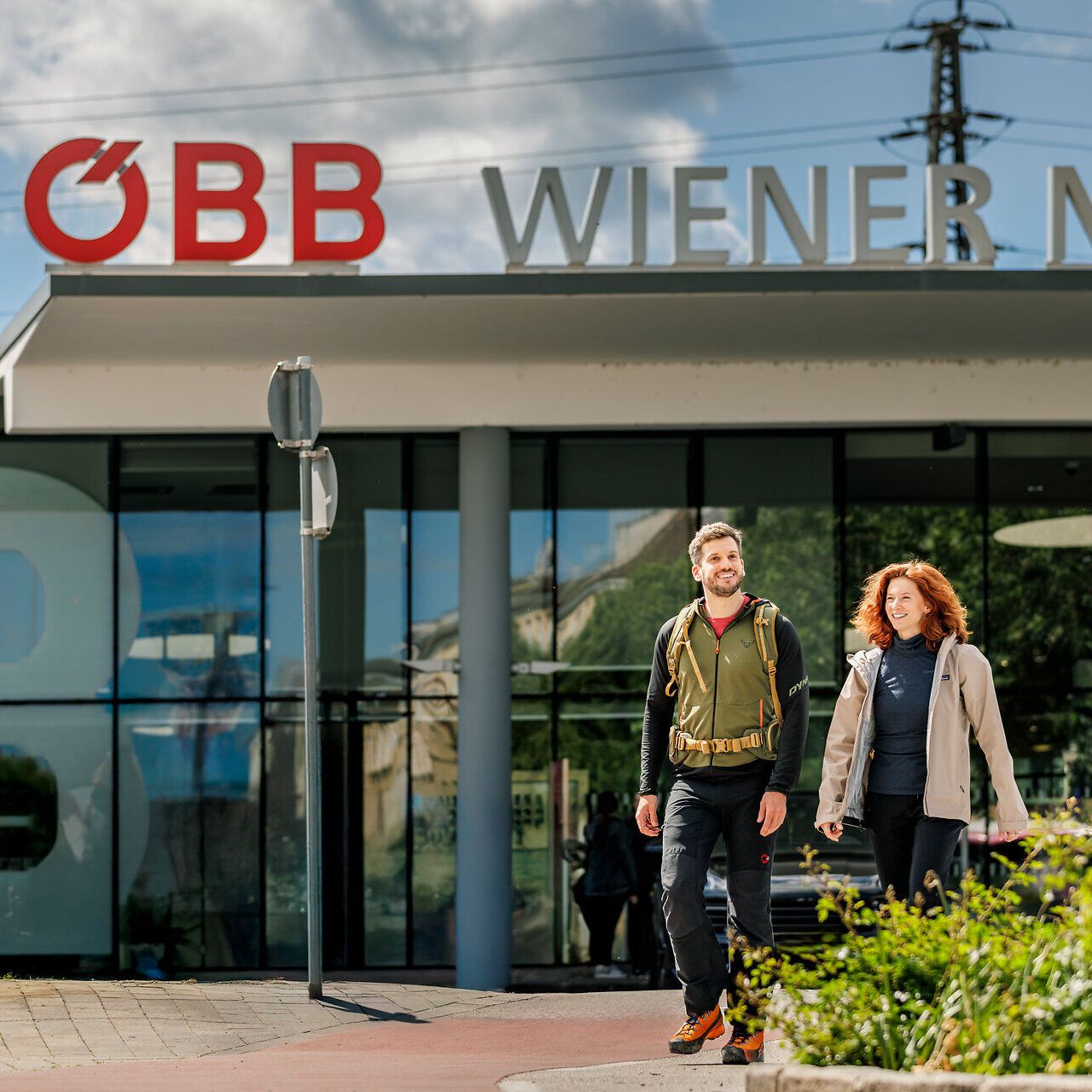 Ein Frau und ein Mann gehen vor dem Bahnhof Wiener Neustadt.