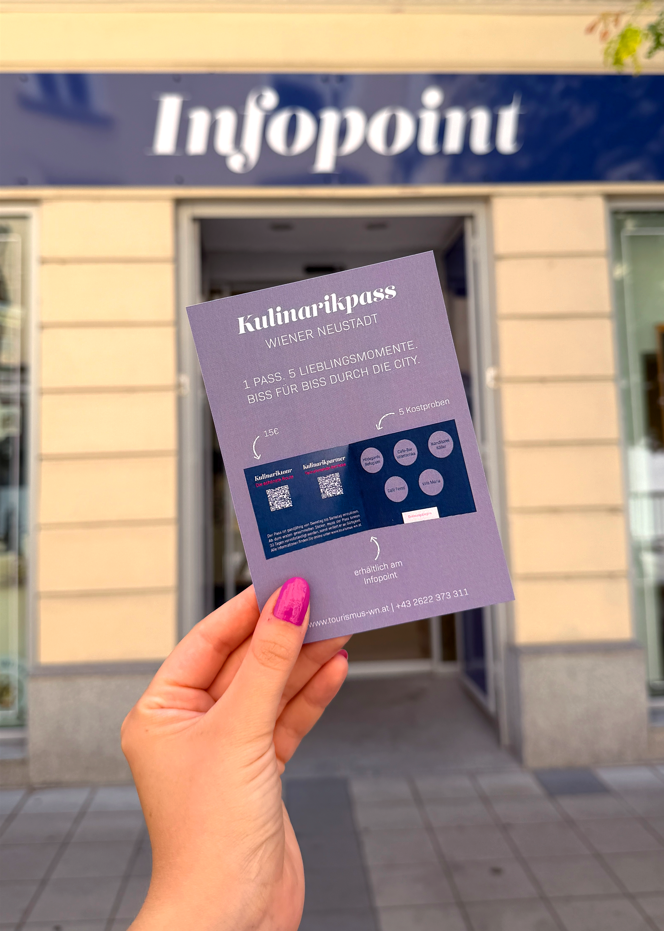 Hand, die einen Flyer vor dem Infopoint hält