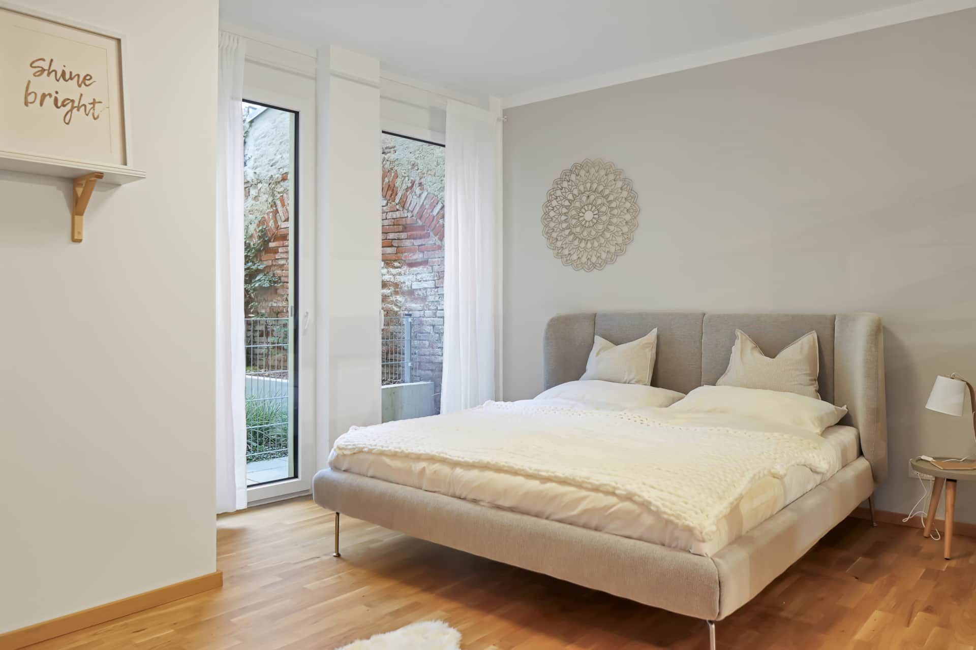 Beiges Schlafzimmer mit großen Fenstern und bequemen Bett