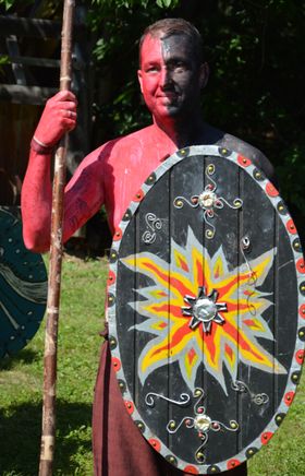 Der Bürgermeister der Gemeinde in rot-schwarzer Körperbemalung, mit Sper und verziertem Holzschild