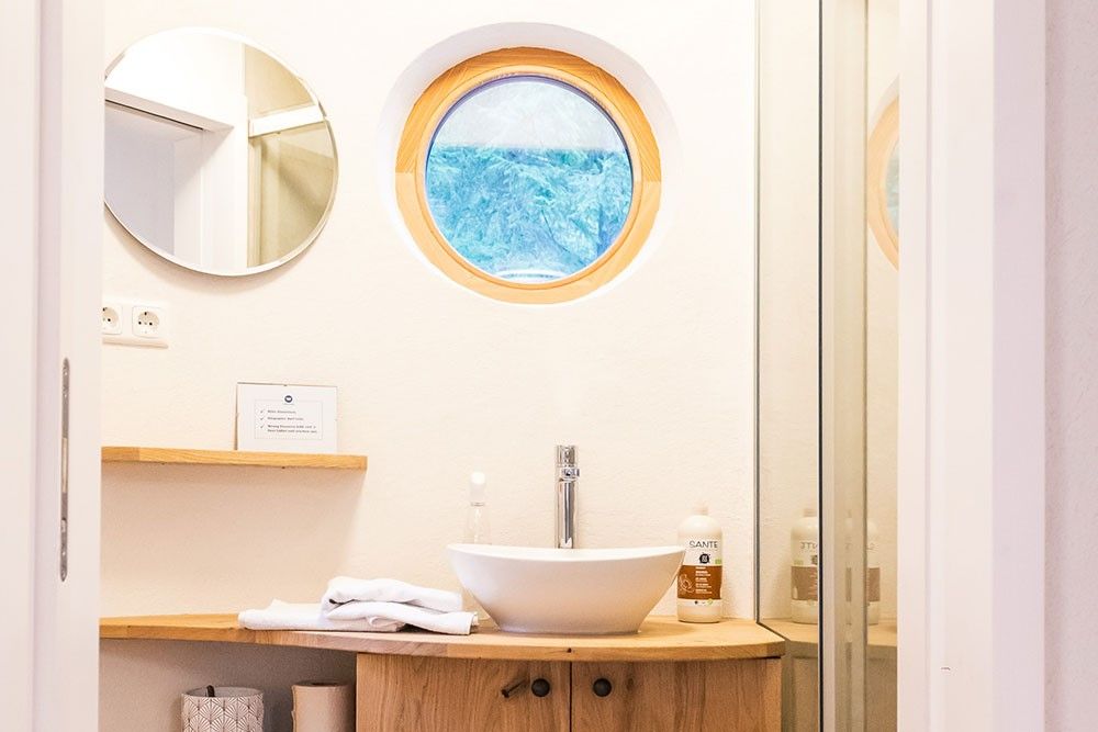 Modernes Badezimmer mit rundem Fenster und Waschbecken.