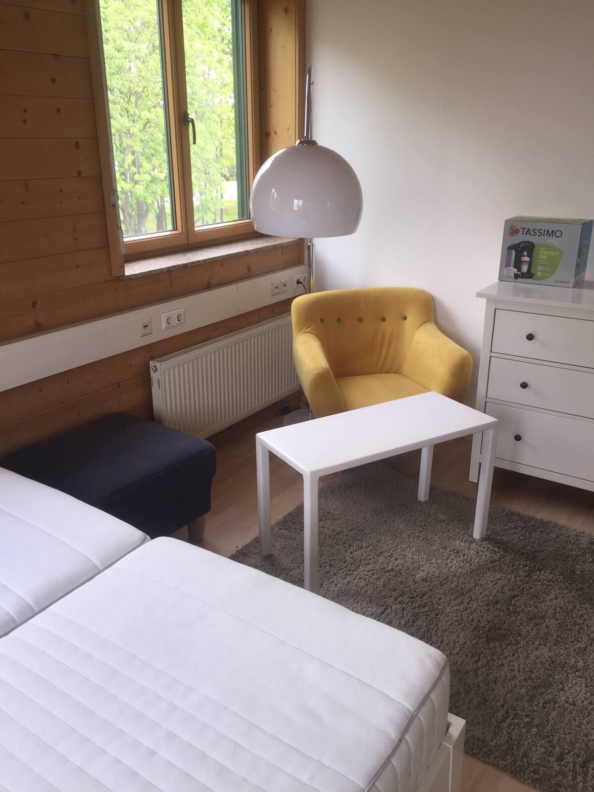 Nette Sitzecke mit gelbem Ohrensessel, Tischchen und Kommode