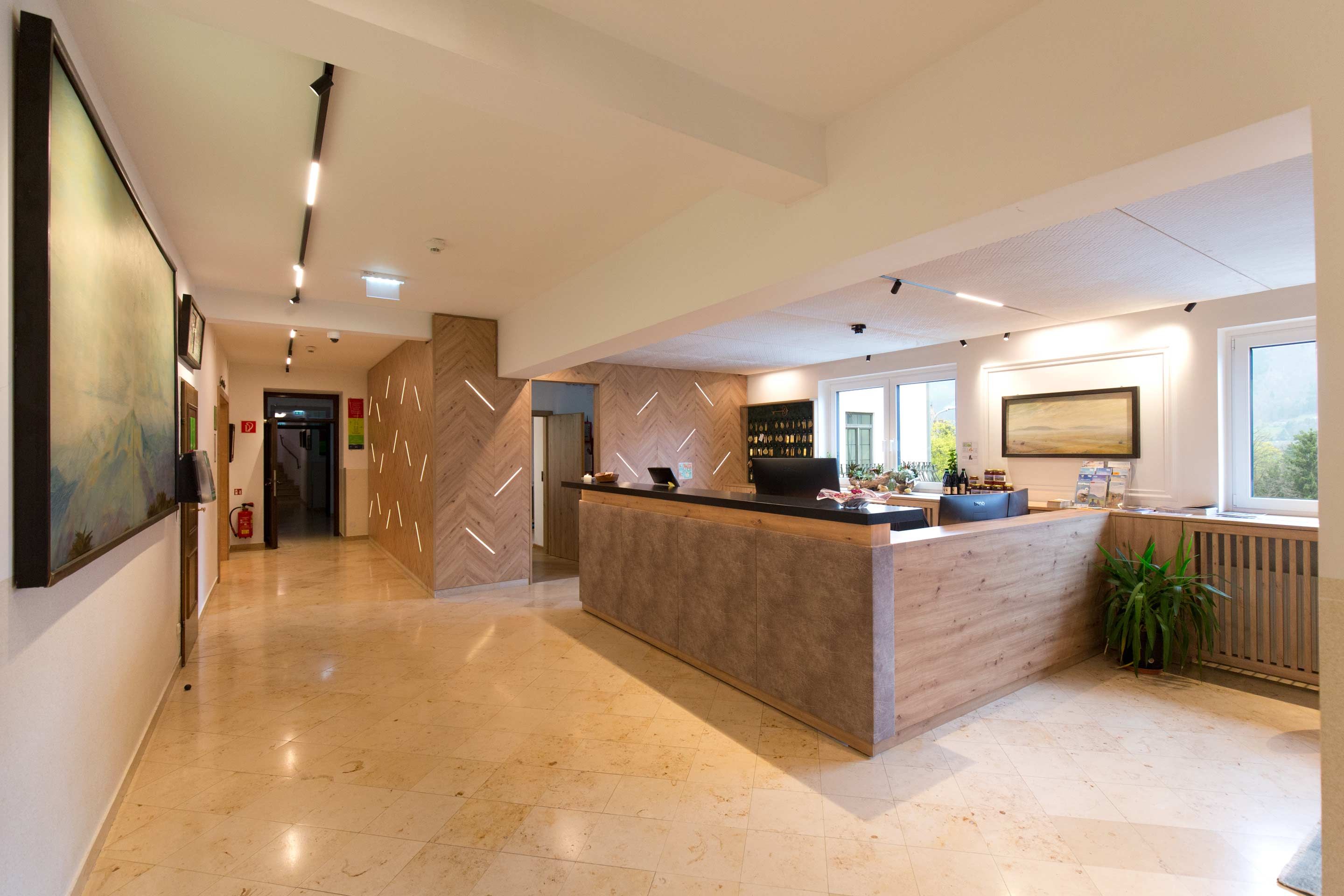 Rezeption eines Hotels mit modernem Design, Holzelementen und einem großen Empfangstresen.