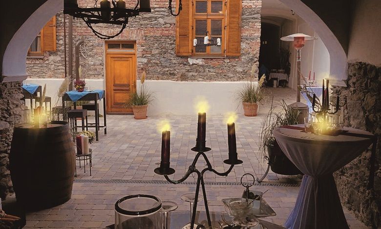 Gemütlicher Innenhof eines Cafés mit Kerzenlicht und rustikaler Steinmauer.