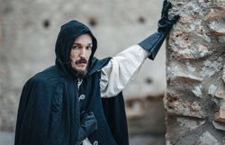 verkleideter Mann im Henkerskostüm lehnt an einem Baum 